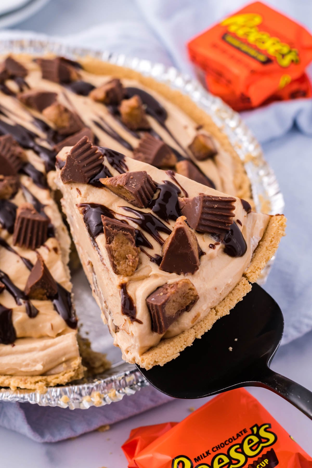 A slice of no bake peanut butter cup pie being removed from the pan with a black spatula.