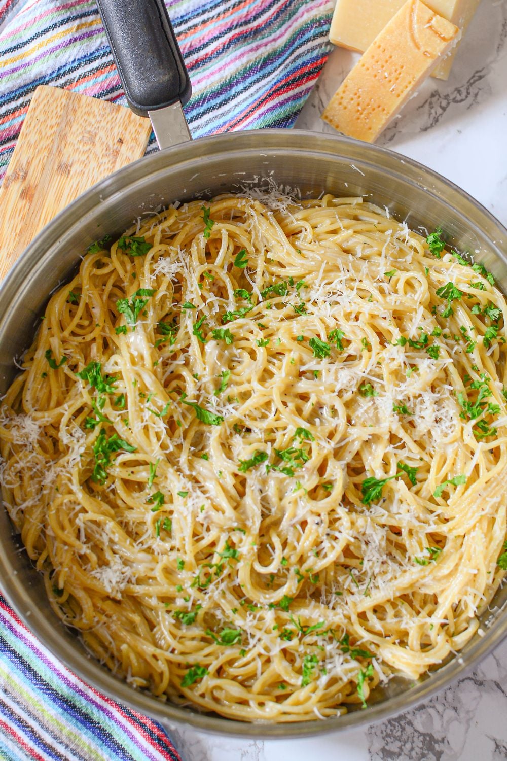 overhead look of skillet full of Garlic Parmesan Pasta and parmesan cheese to side of pan