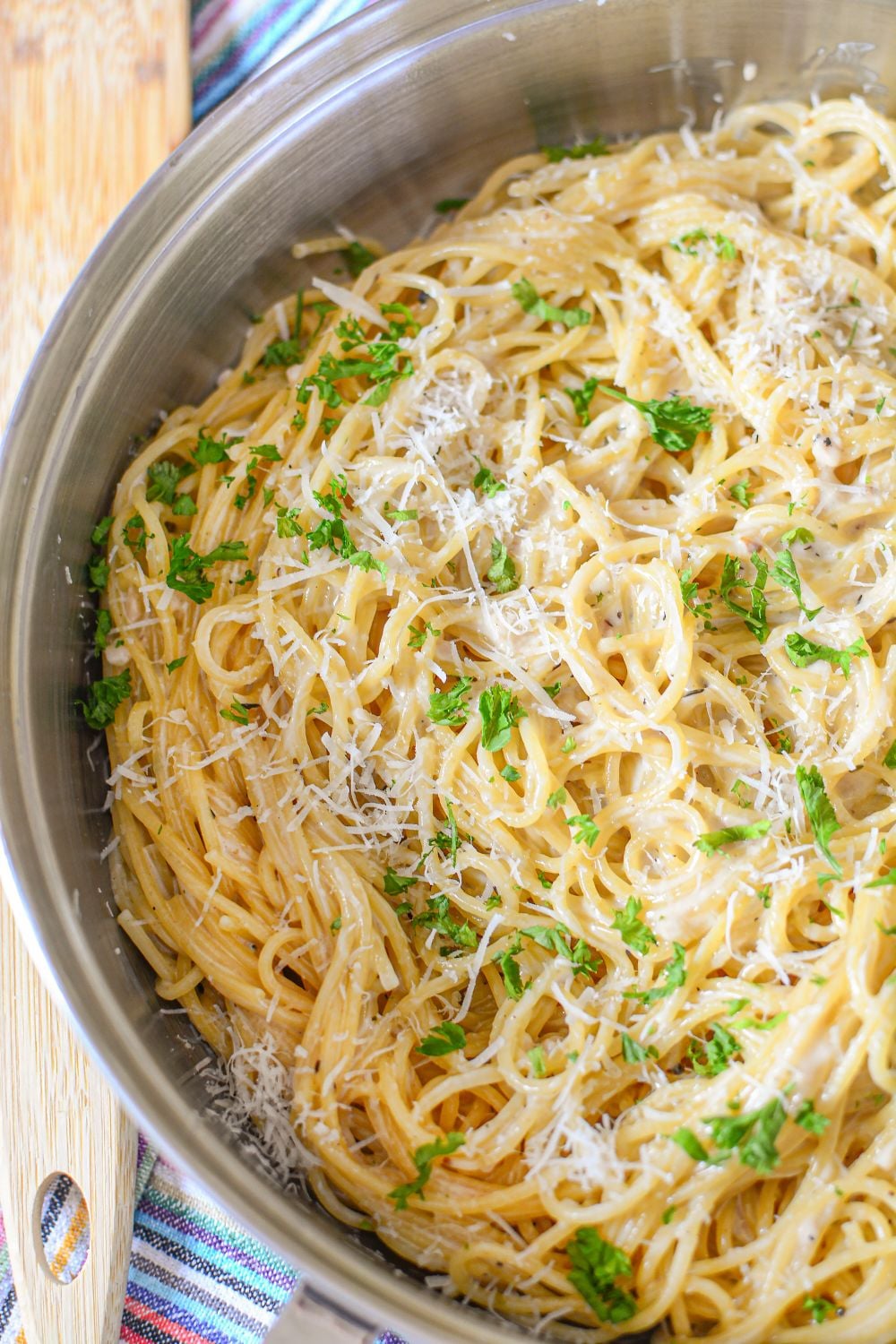skillet on table with some cheesy parmesan pasta topped with parsley