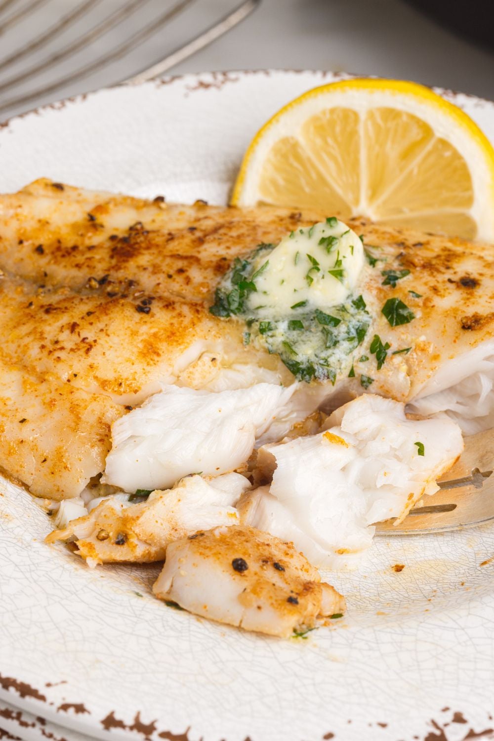 Pan Fried Tilapia on plate with pieces cut out of it