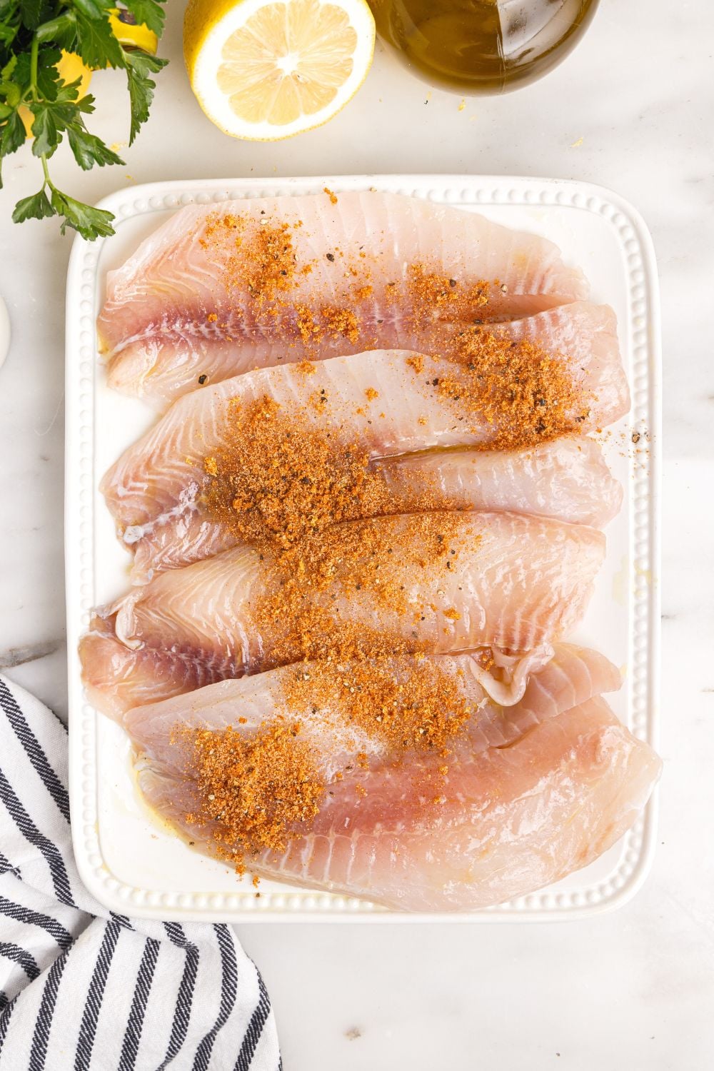 tilapia on cutting board with seasoning on it