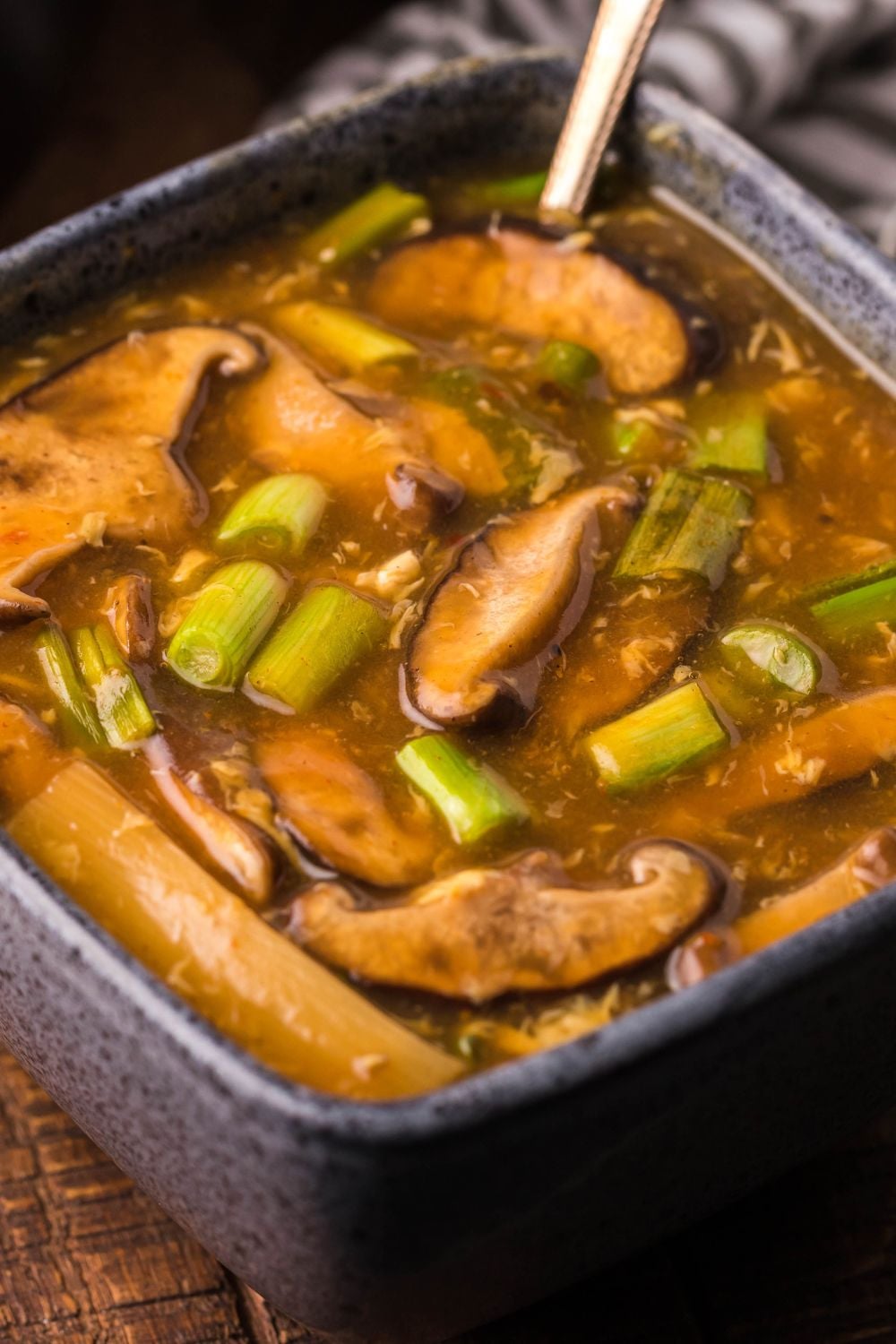 PF Changs Hot And Sour Soup in a square bowl with a spoon in bowl