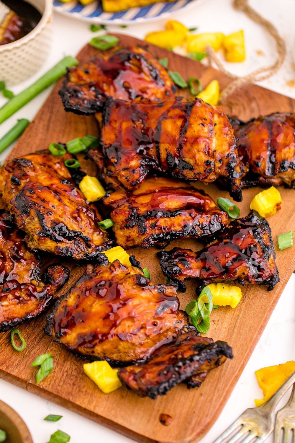 table with a platter of Huli Huli Chicken on it and garnished with green onions