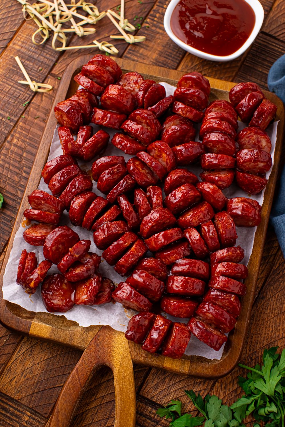 BBQ Hasselback Smoked Sausages on a cutting board with a bowl of sauce
