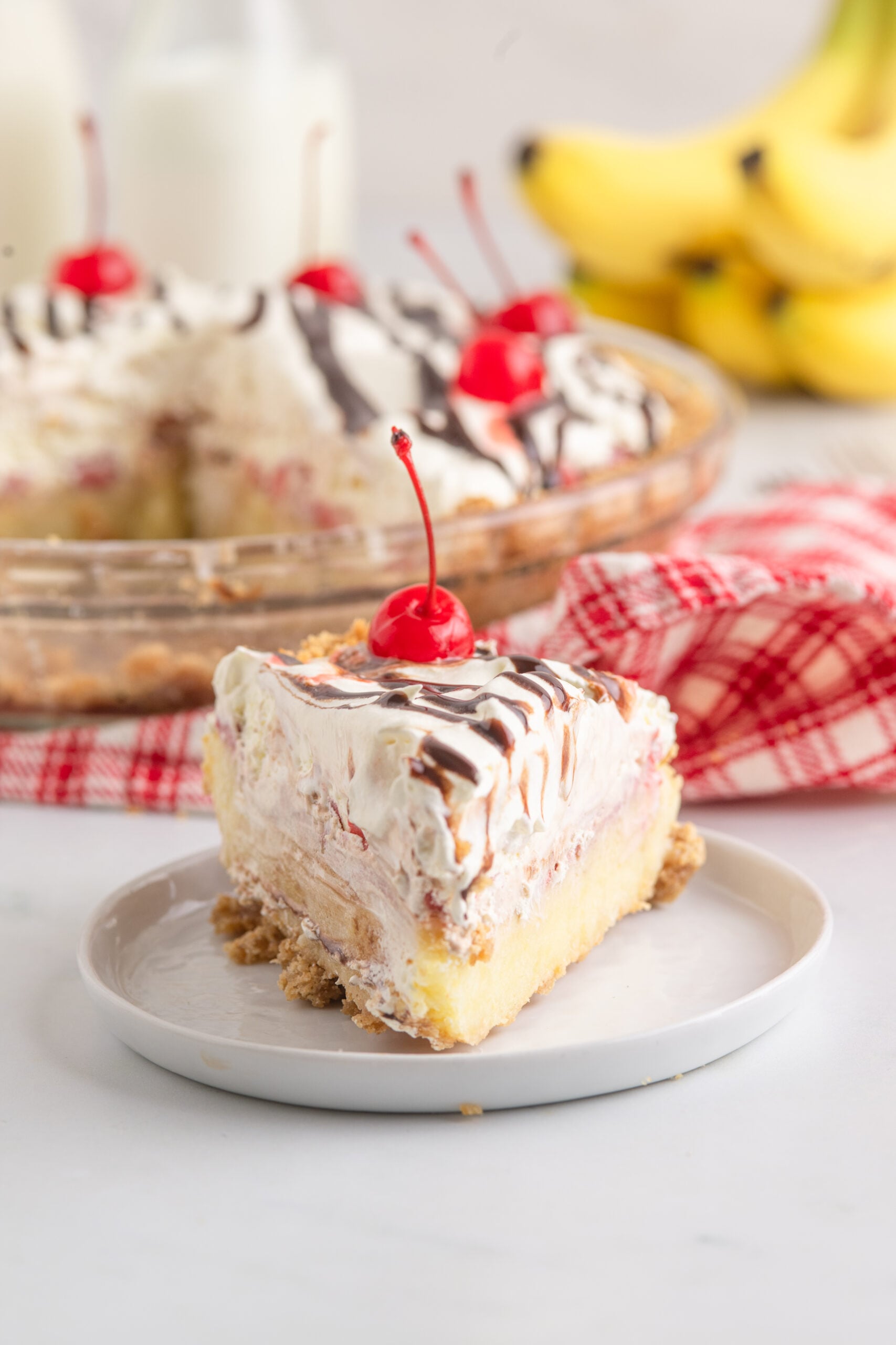 No Bake Banana Split Pie on a white plate with the whole pie in the background