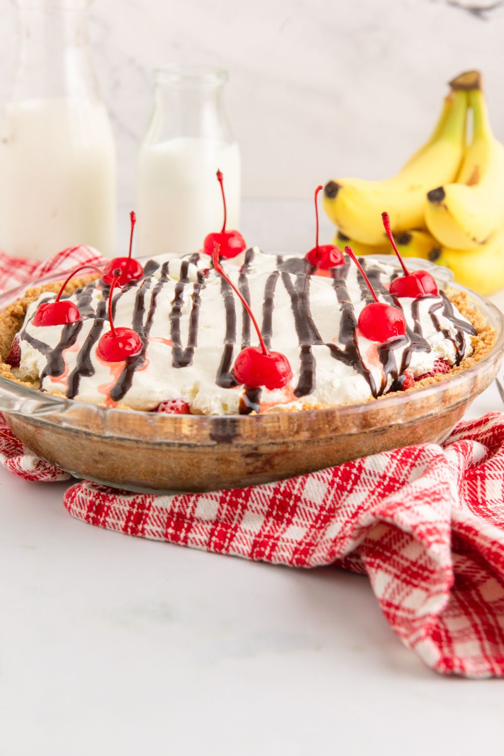 side view of no bake banana split pie on table with bundle of bananas to side