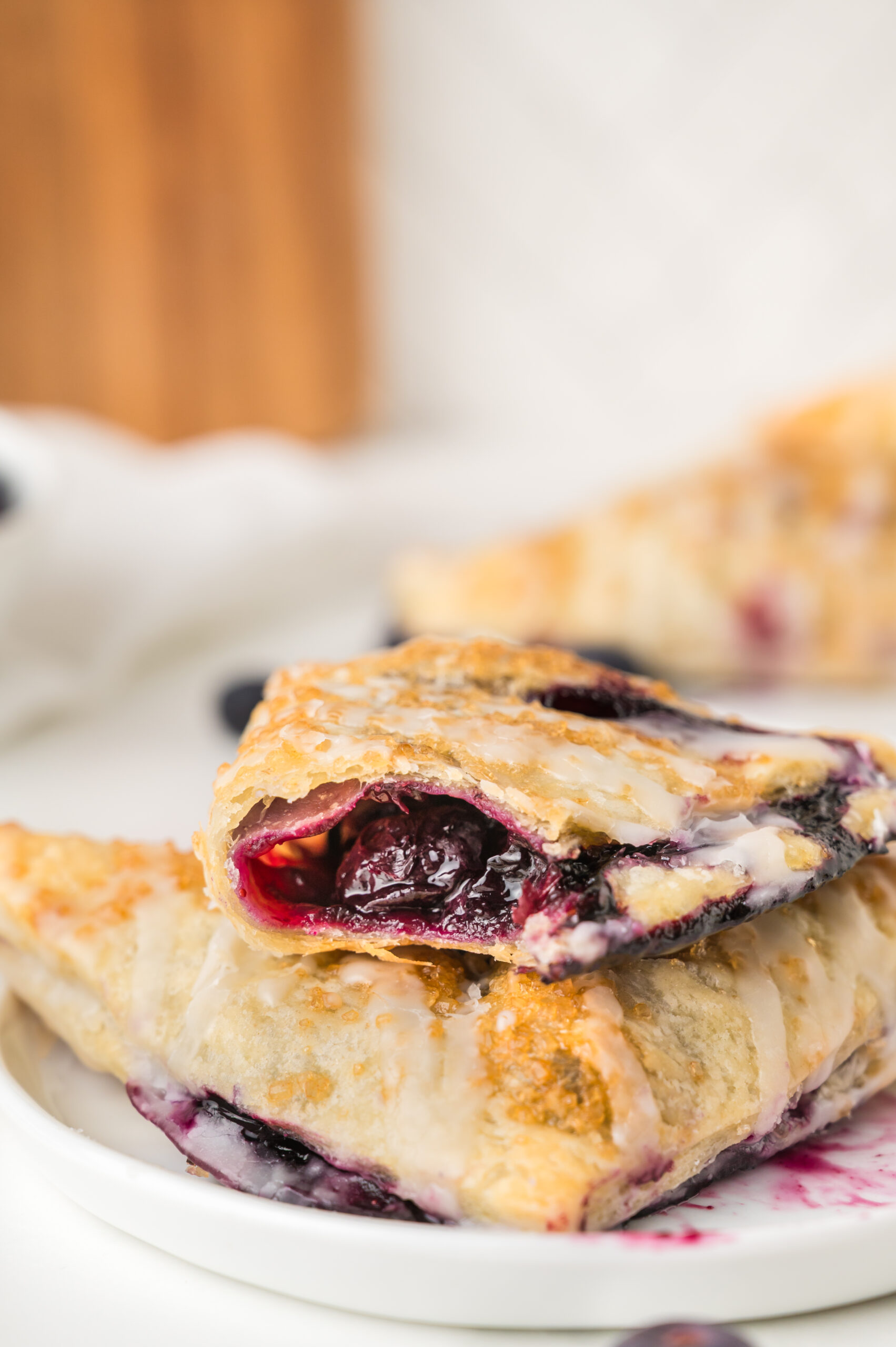 Blueberry Turnovers on plate with a bite missing drizzled with icing