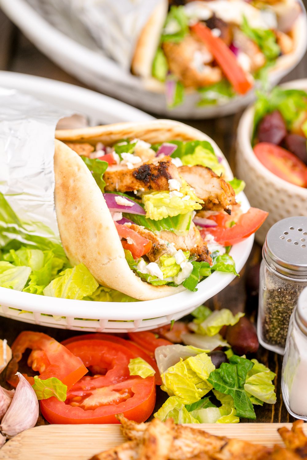 plate with chicken gyros with fresh veggies on top in a pita