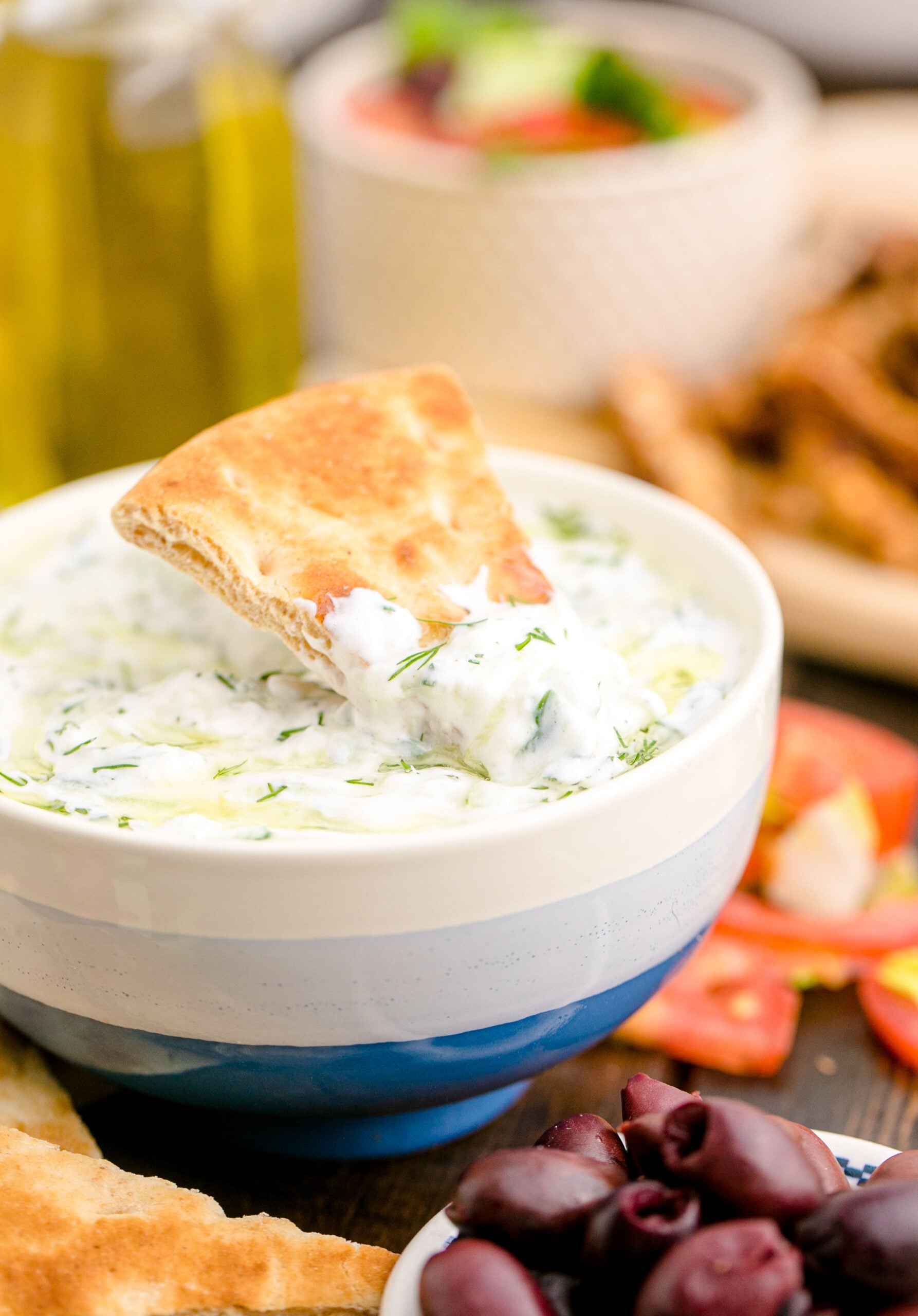 Tzatziki Sauce in a white and blue bowl with a pita chip in it
