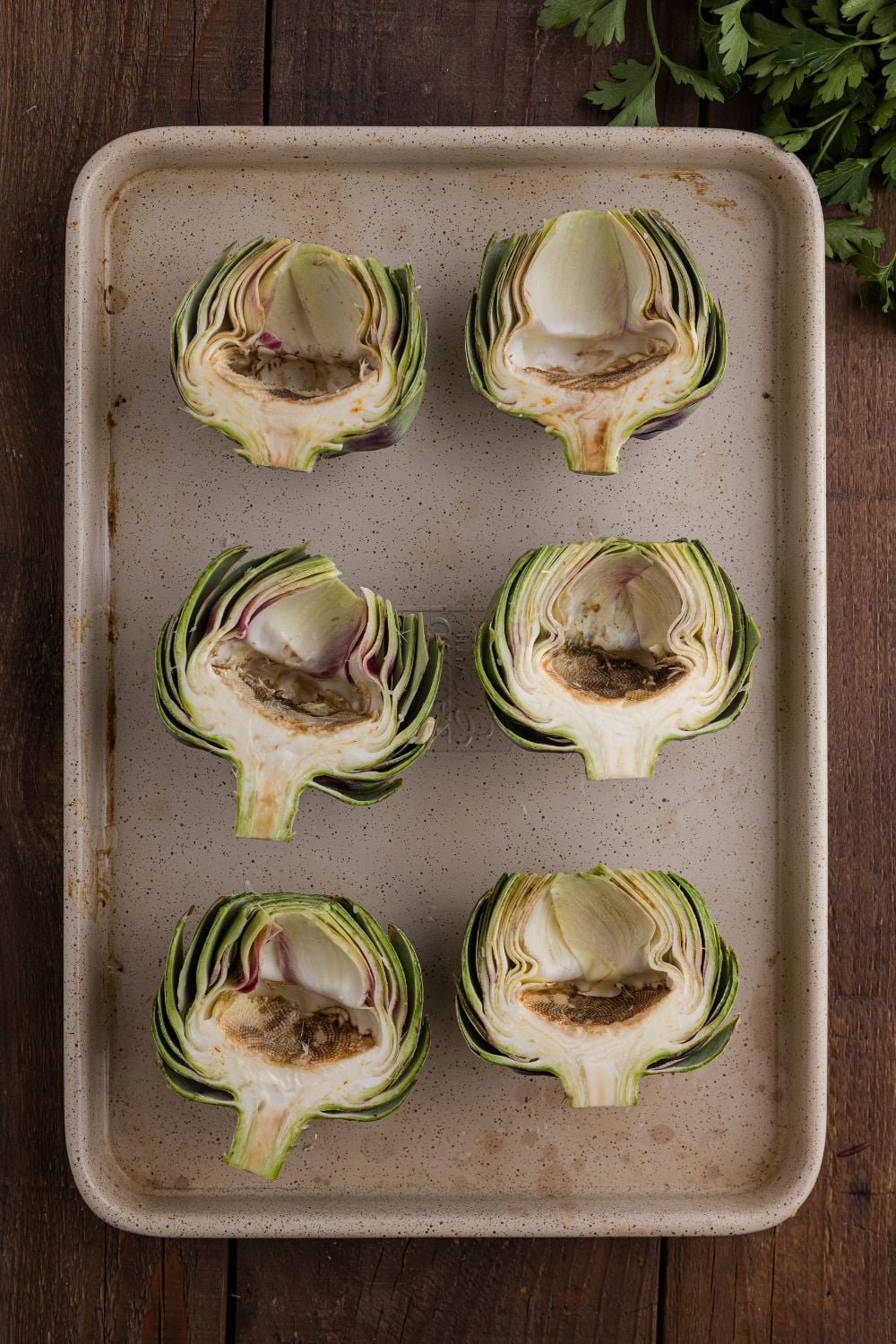 sliced artichokes sitting face up on a baking tray