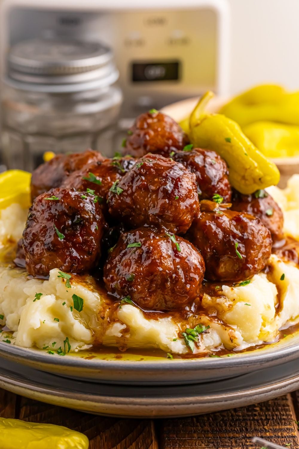plates stacked with Crockpot Mississippi Meatballs and mashed potatoes piled on a plate