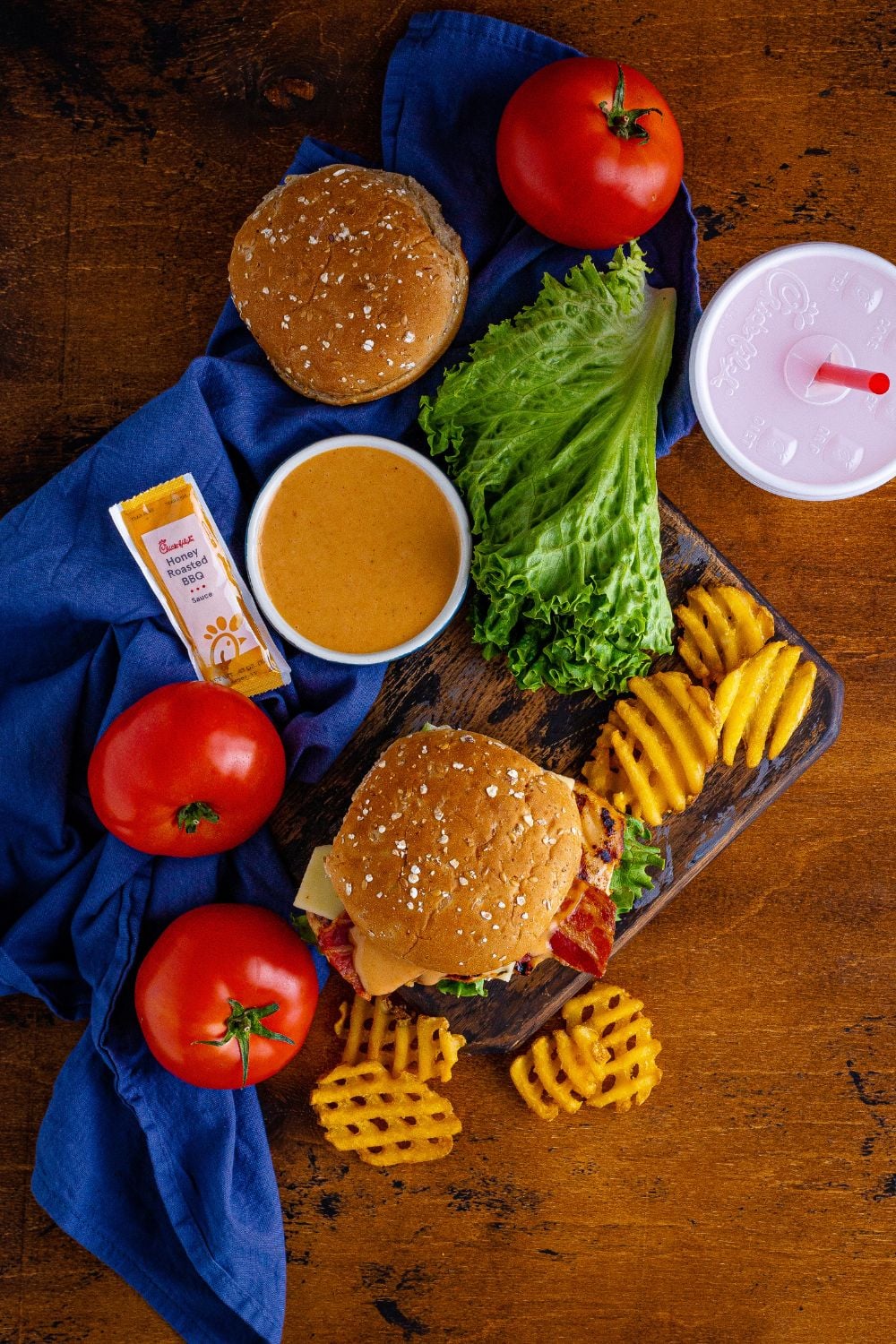 overhead look of table with Chick Fil A Grilled Chicken Sandwiches on it, drinks, french fries, and more