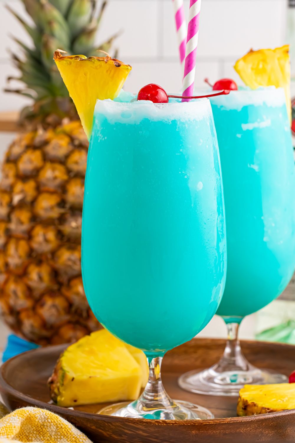 Frozen Blue Hawaiian Cocktails on table with pineapples around the table 
