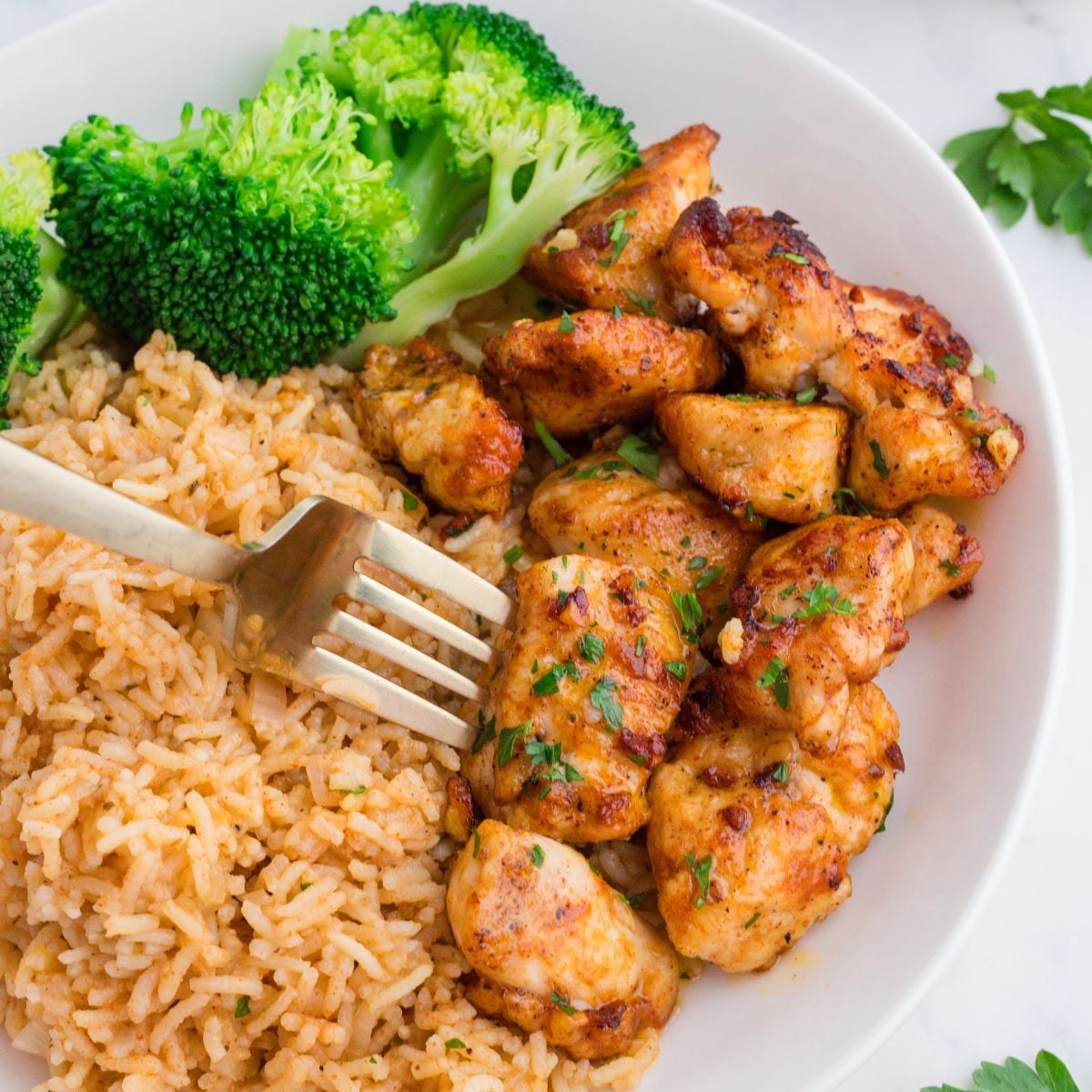 Garlic Butter Chicken Bites on plate with rice and broccoli on side of it
