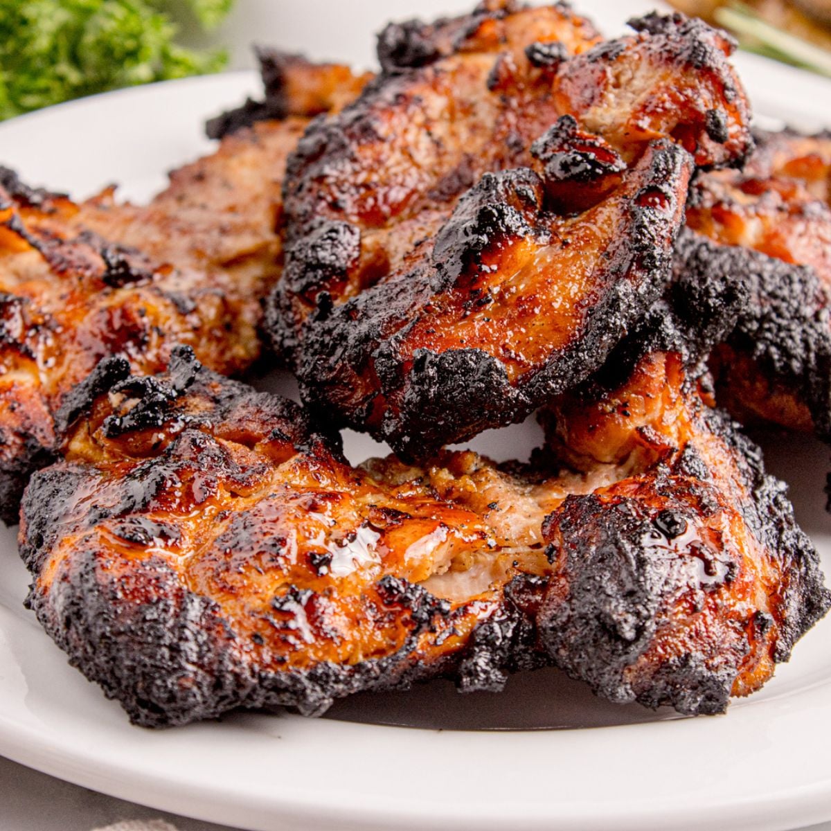 Grilled Chicken Thighs on plate with chicken stacked on top of it 