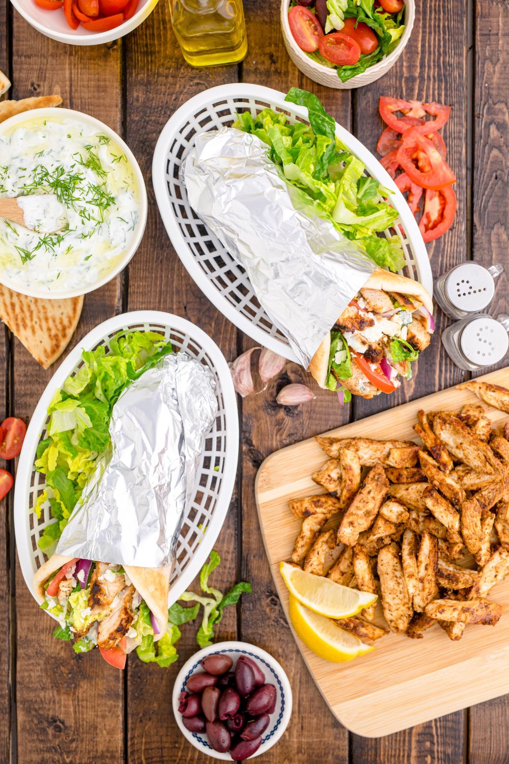 overhead look of chicken gyros in baskets with fresh veggies around it on table