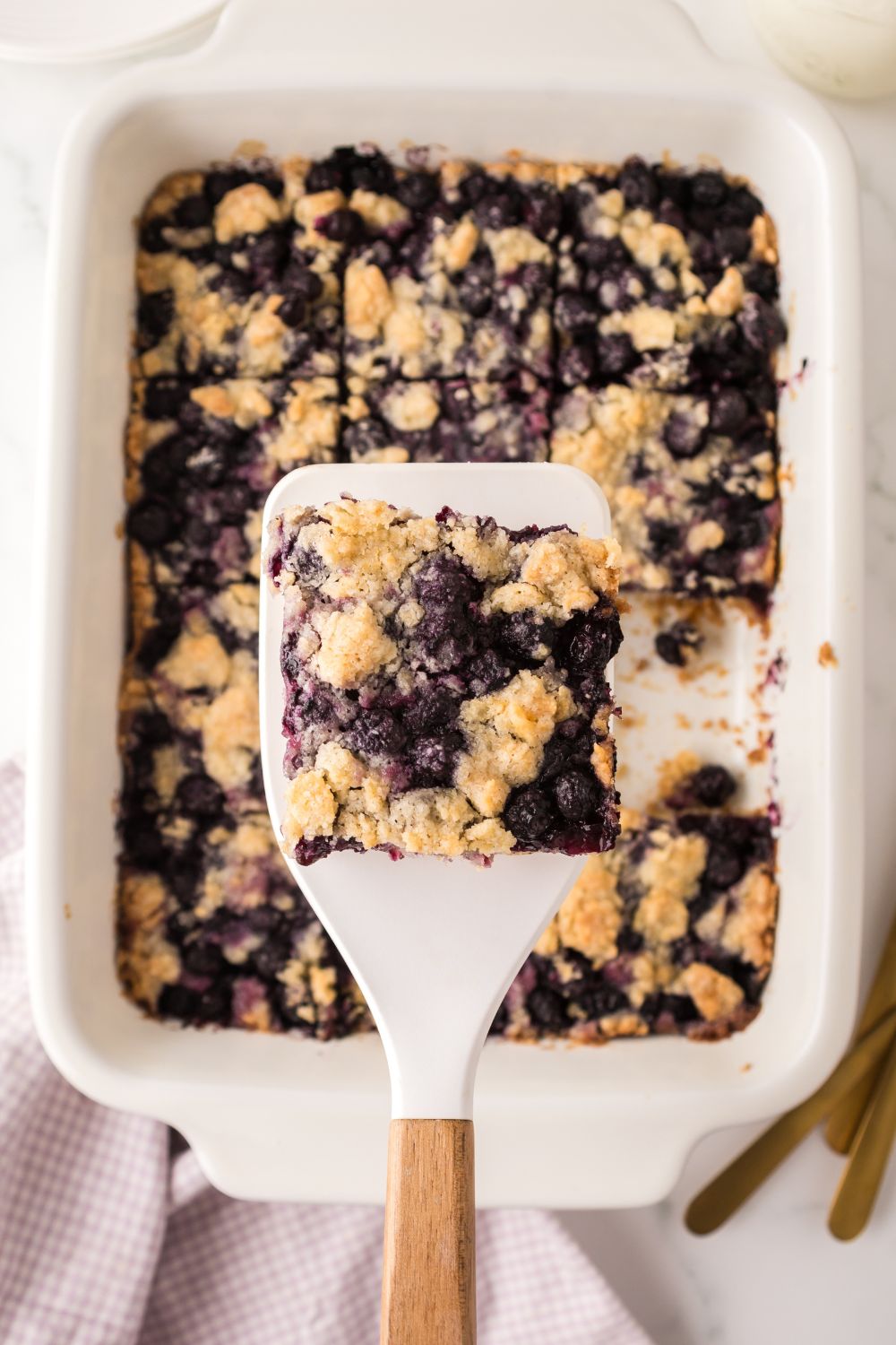 Blueberry Crumb Bar on a spatula above the casserole dish
