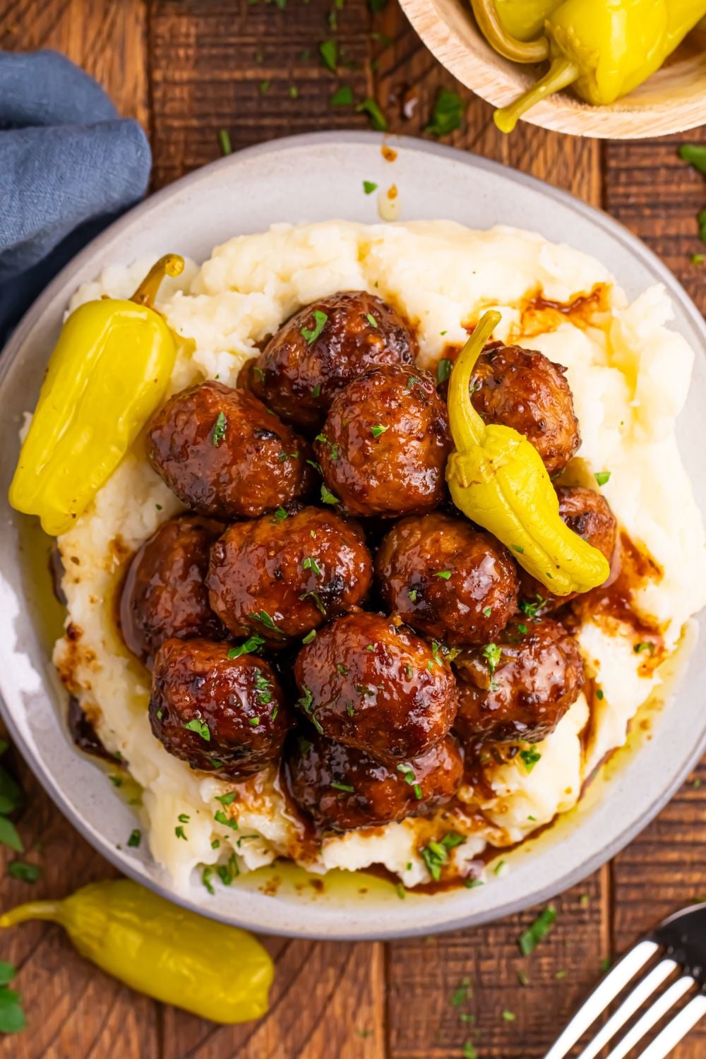Crockpot Mississippi Meatballs on a plate with mashed potatoes underneath a fork to the side on table