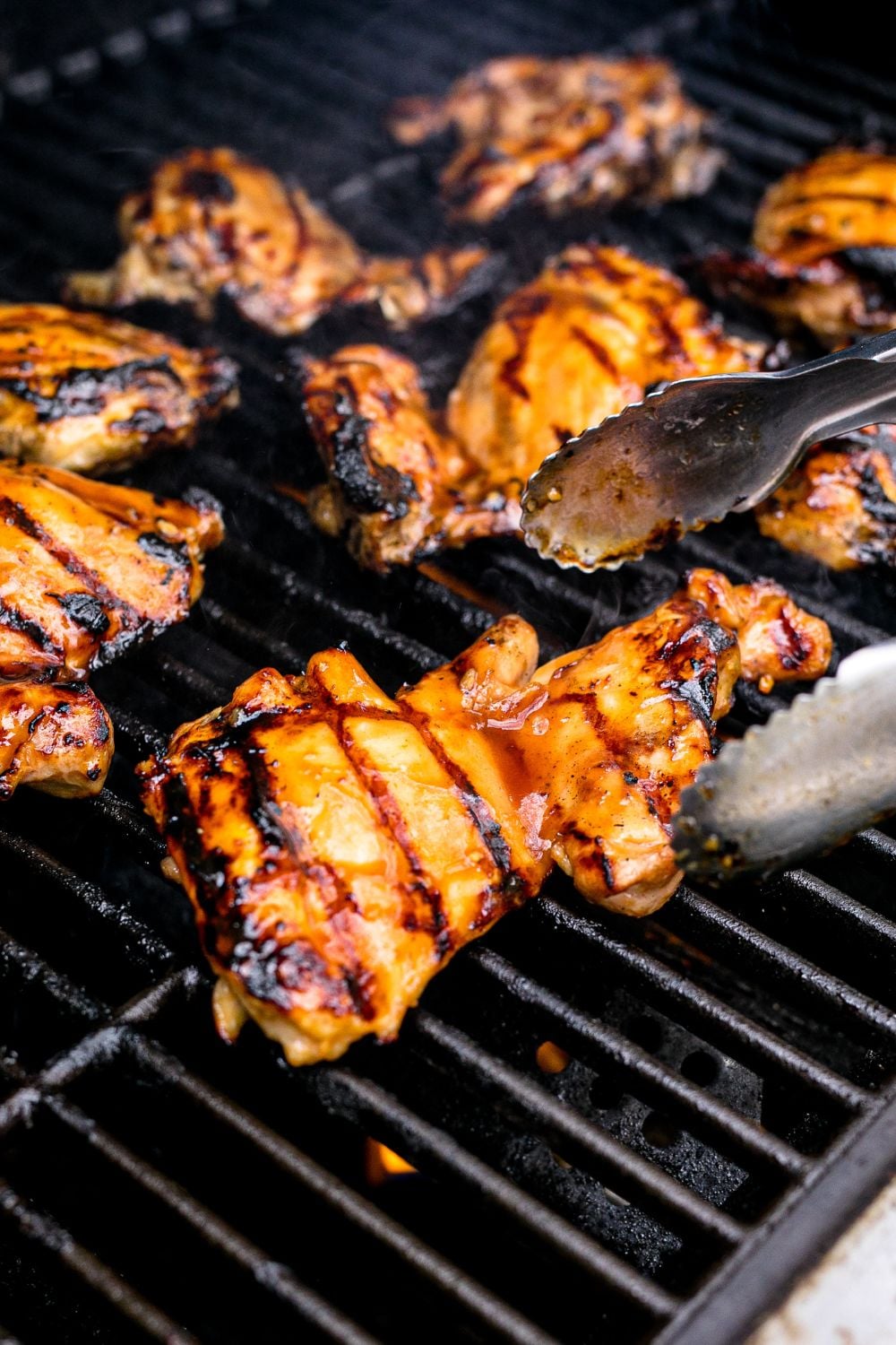 Huli Huli Chicken on a grill with tongs by chicken