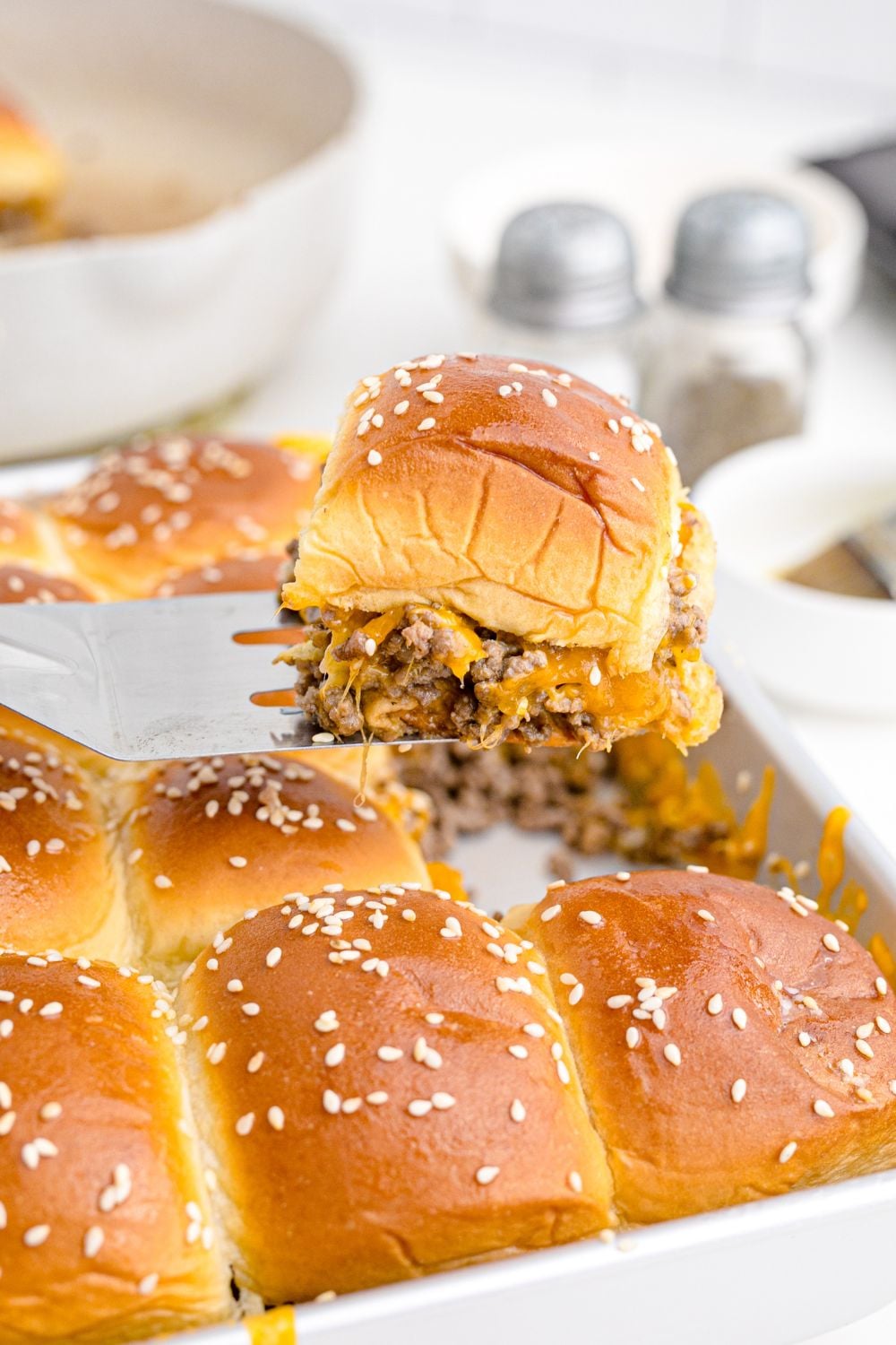 Classic Cheeseburger Slider being lifted out of pan with the rest of the sliders