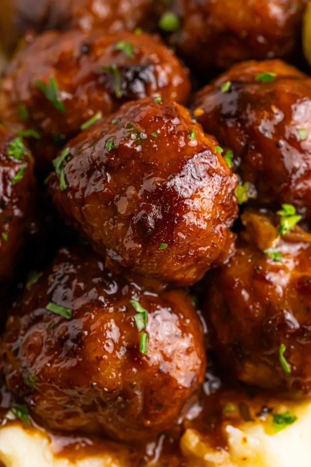 close up of a stack of Crockpot Mississippi Meatballs on a plate on table with garnish