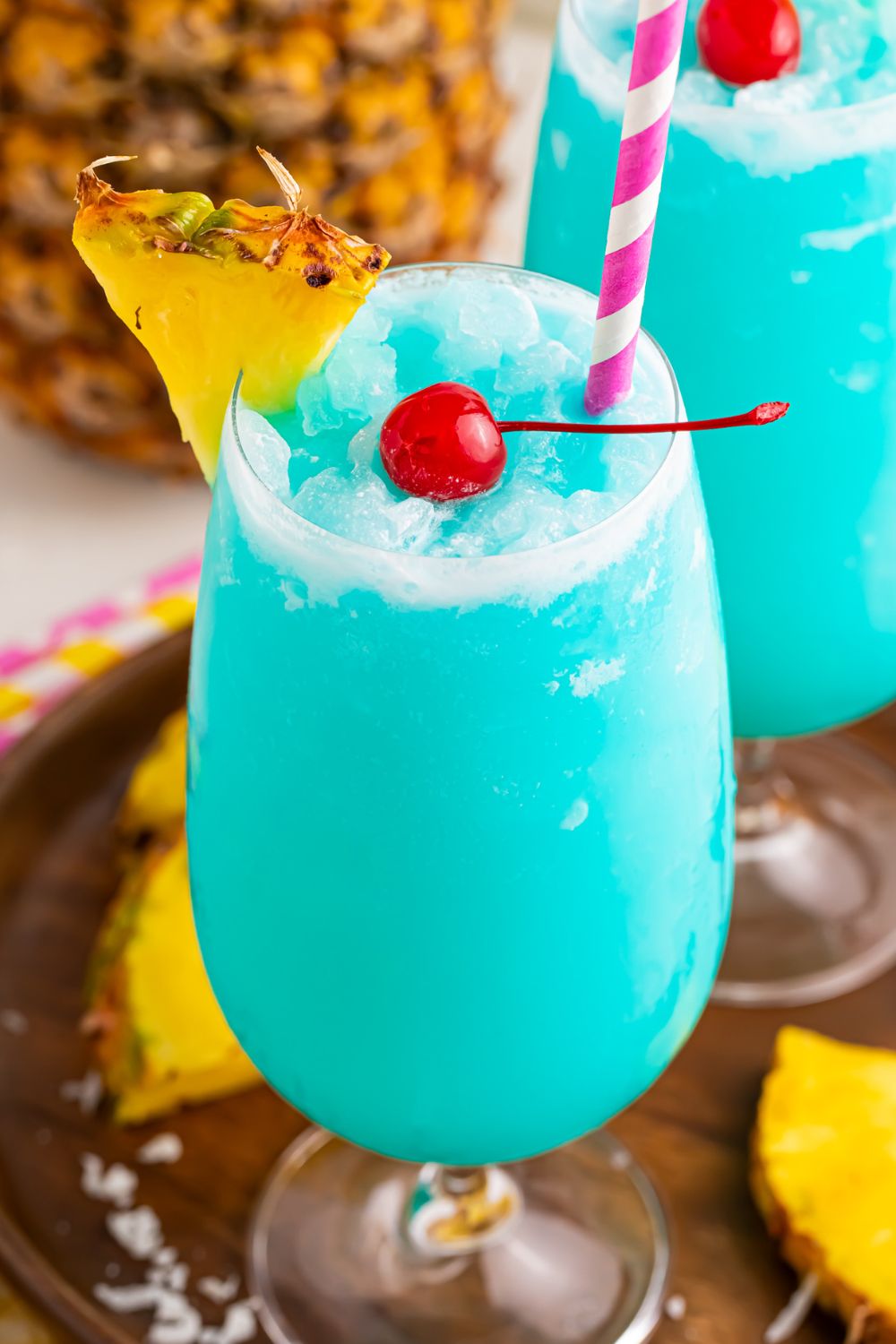 Frozen Blue Hawaiian Cocktails in glasses with pineapple slices 