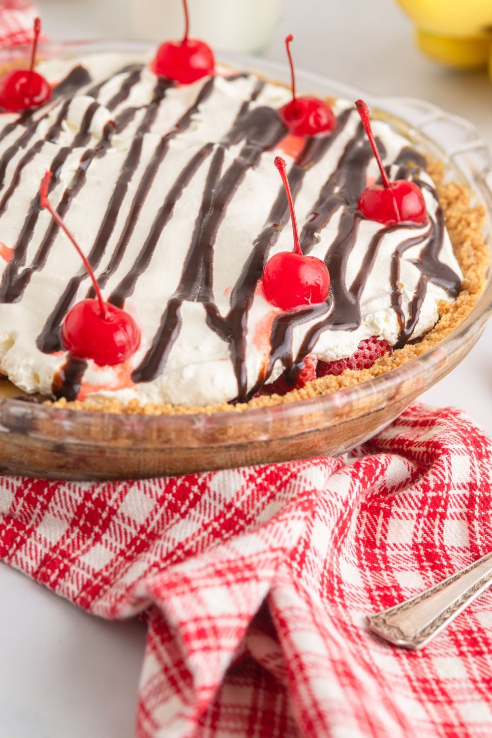 side view of No Bake Banana Split Pie on table with a checked towel under it