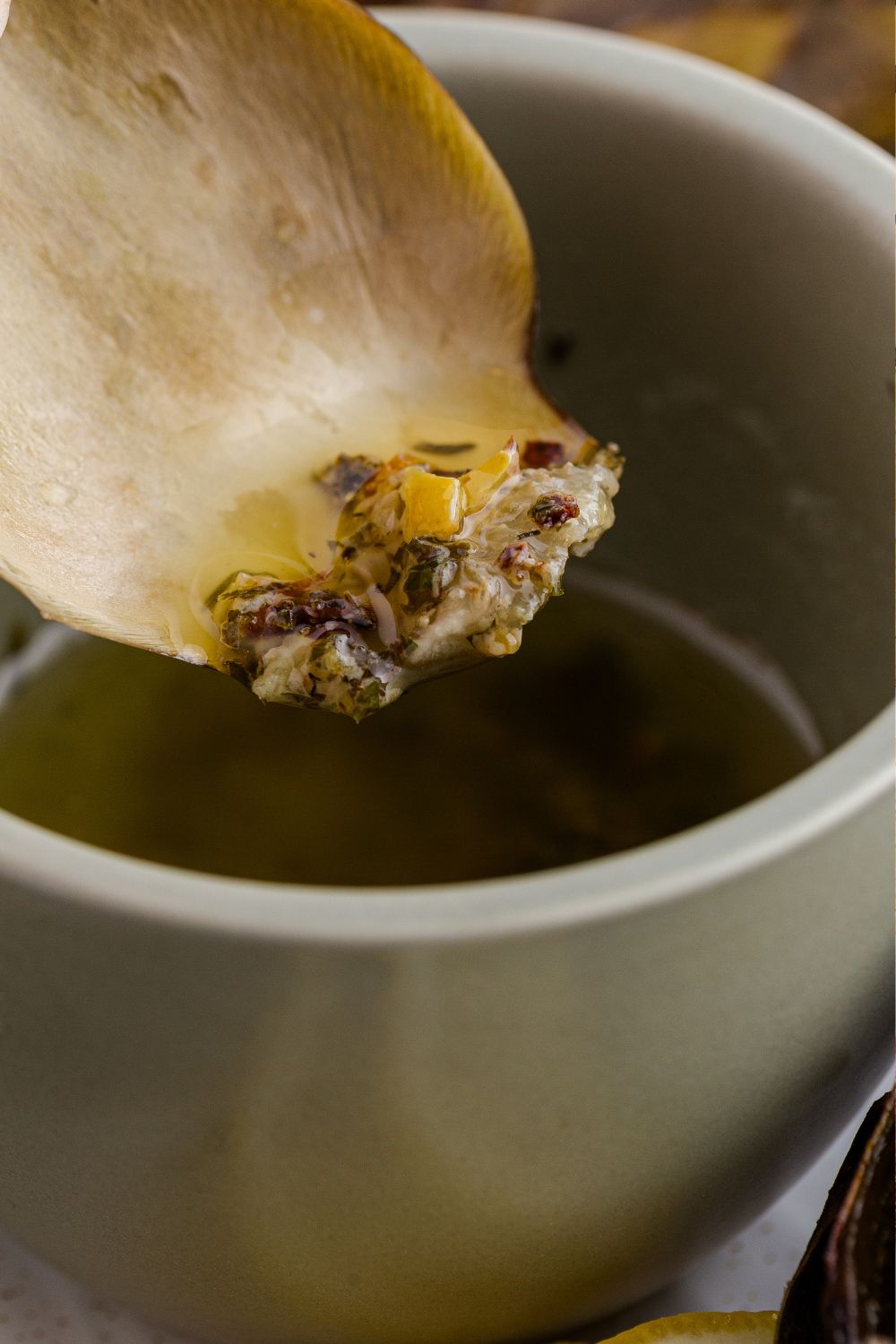 artichoke dipped in oil mixture from a bowl