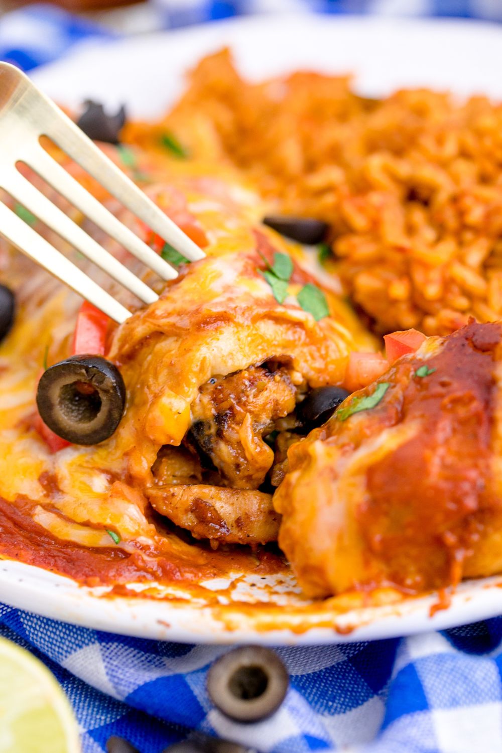 fork taking a bite out of a plate with Cheesy Chicken Enchiladas