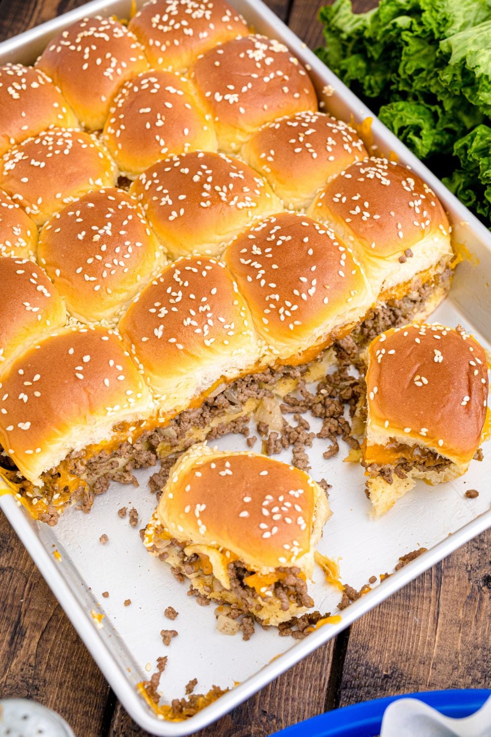 Classic Cheeseburger Sliders in a casserole dish with a few sliders gone out of pan already