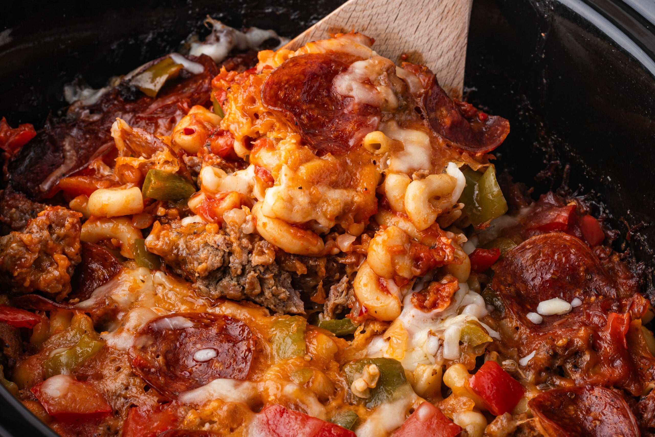 spoon lifting up some of the Slow Cooker Pizza Casserole out of the crock pot