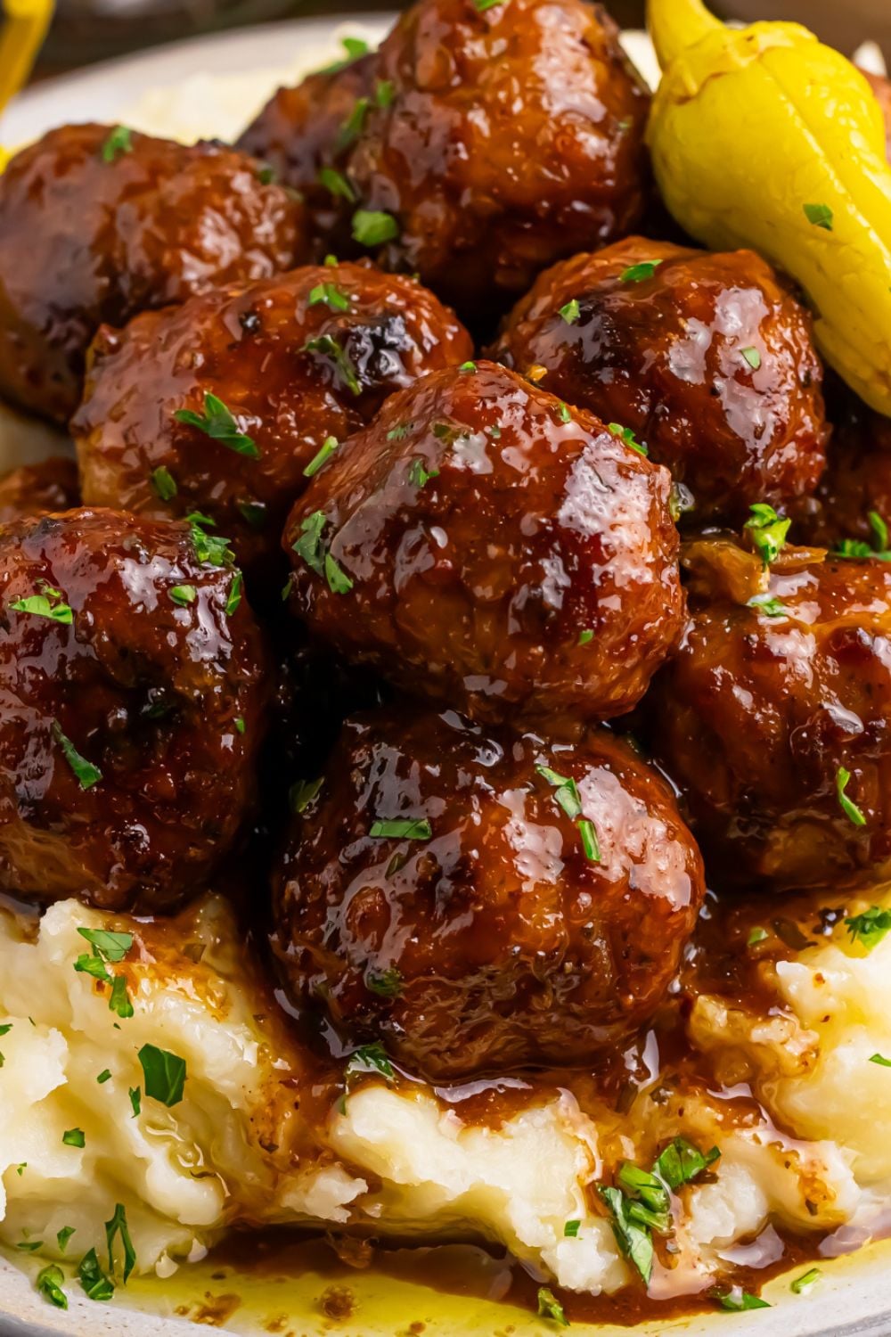 close up of Crockpot Mississippi Meatballs on plate with mashed potatoes under the meatballs