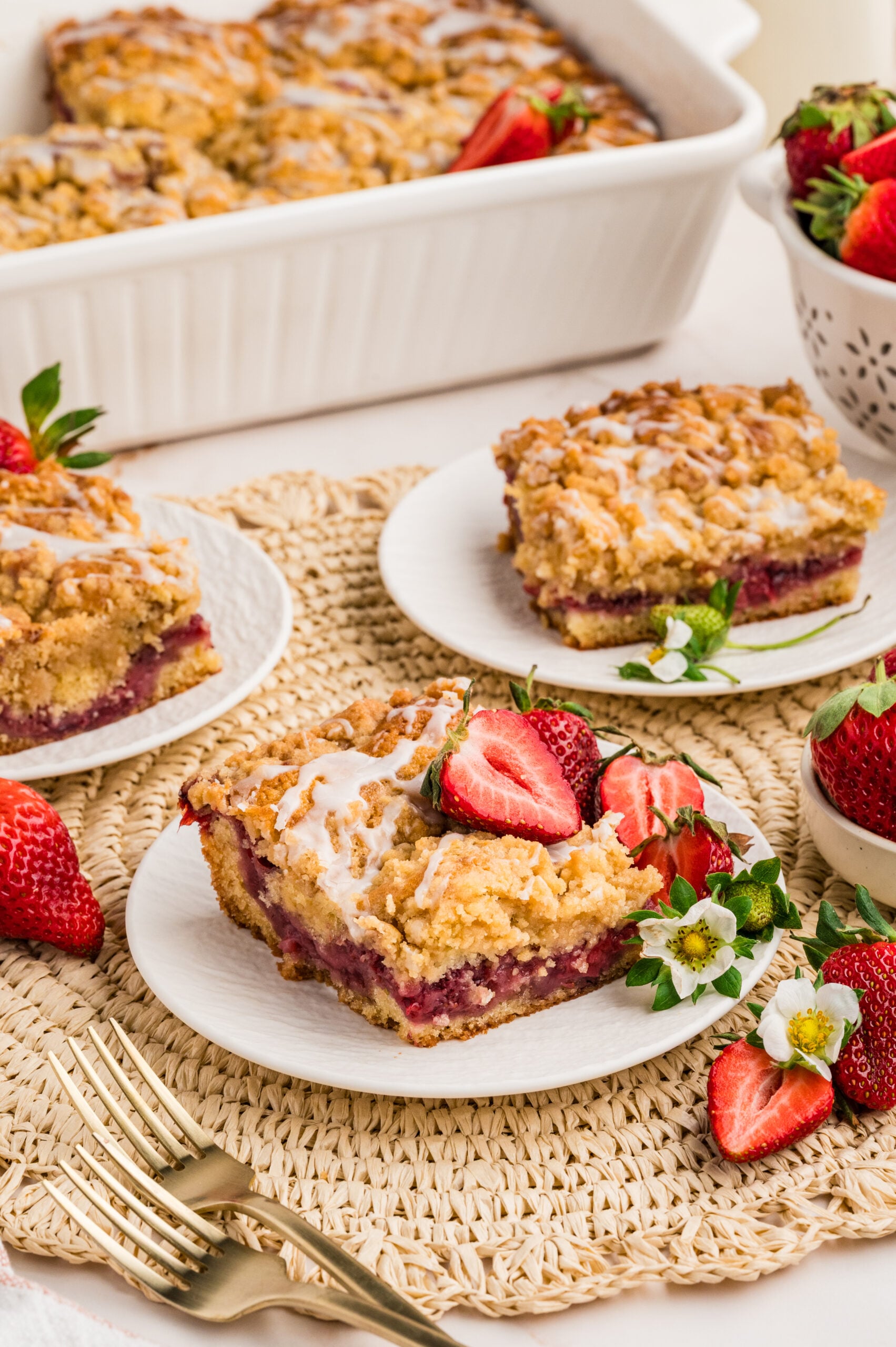 Strawberry Coffee Cake on a white plate with sliced strawberries and little flowers