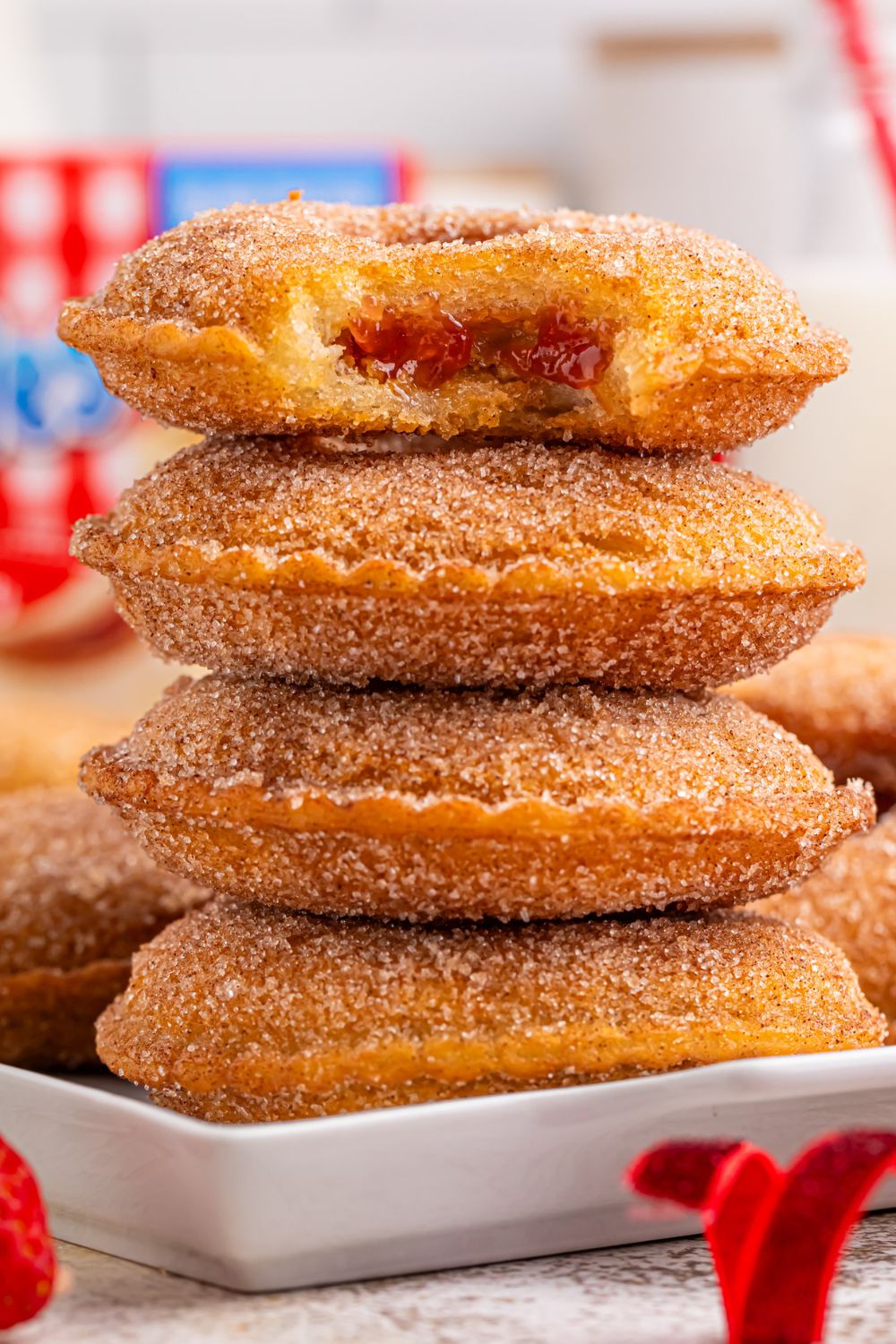 stack of Fried Strawberry Uncrustables on plate with top one that has a bite taken out of it 