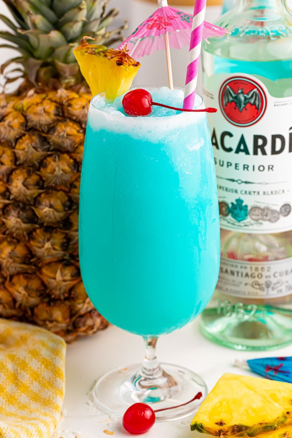 Frozen Blue Hawaiian Cocktail on table with bottle of rum and pineapple 