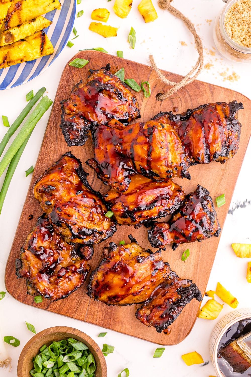 overhead look down on table with Huli Huli Chicken in center, with green onions, pineapple and more around the table