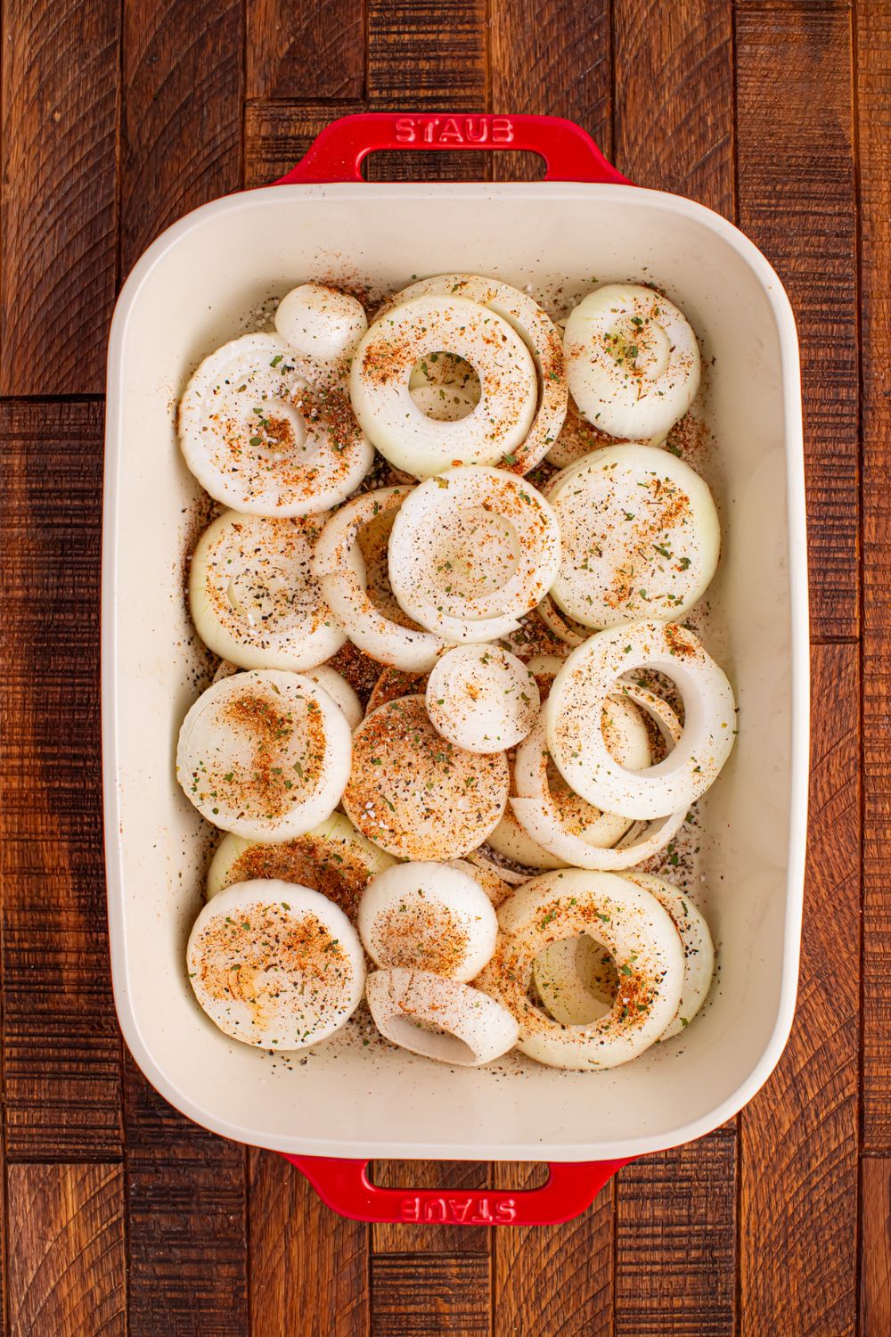 sliced onions in a casserole dish with seasonings on top