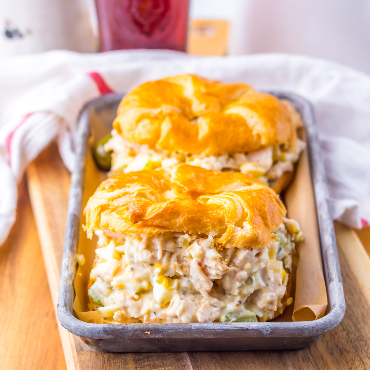 Side view of two chicken salad sandwiches on a tin tray. 