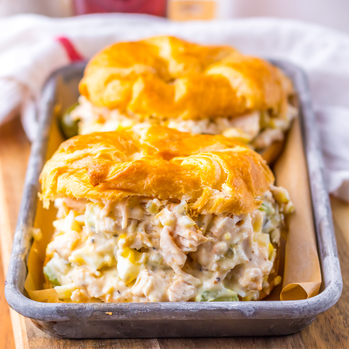Side view of two chicken salad sandwiches on a tin tray. 