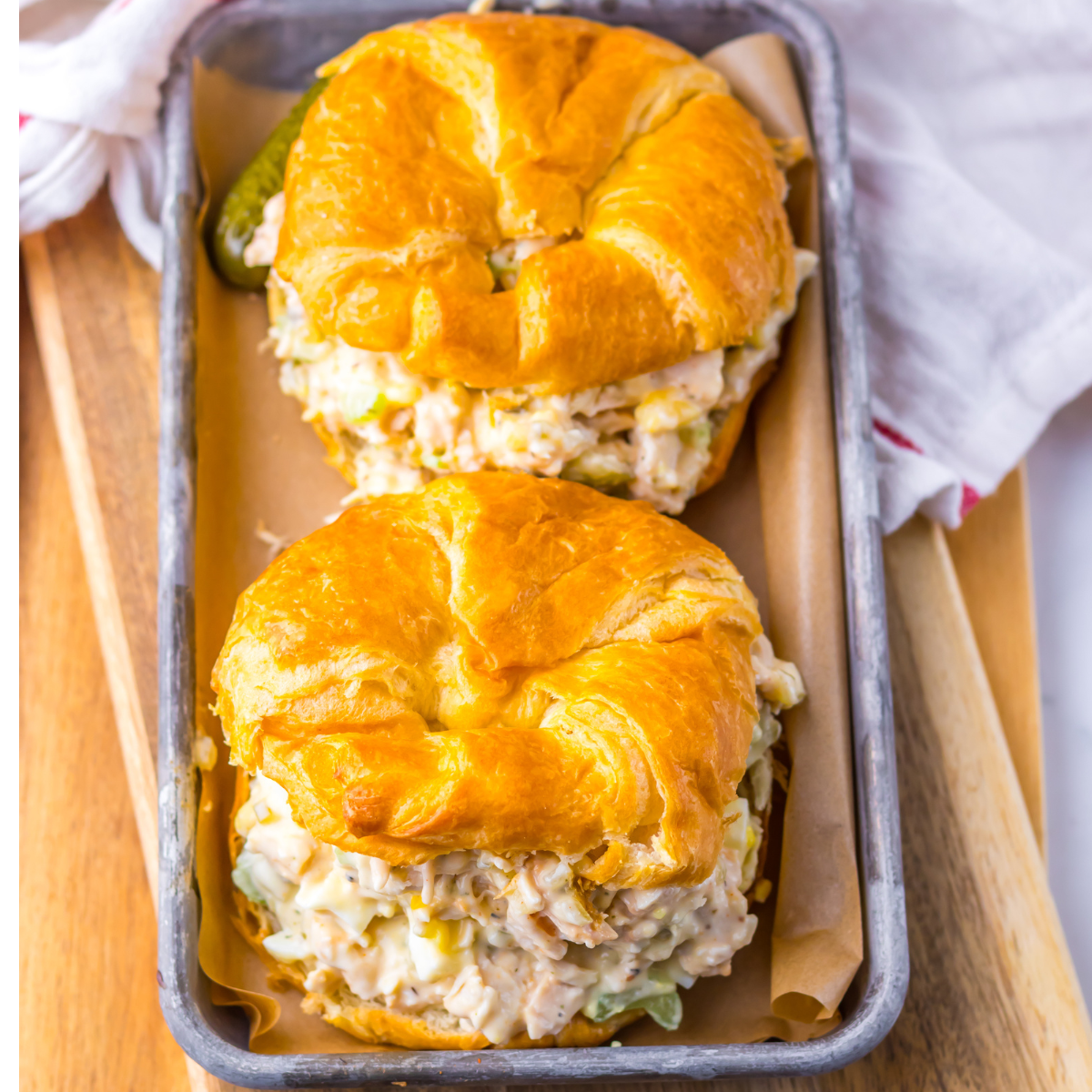Overhead view of two chicken salad croissants on a tin tray. 