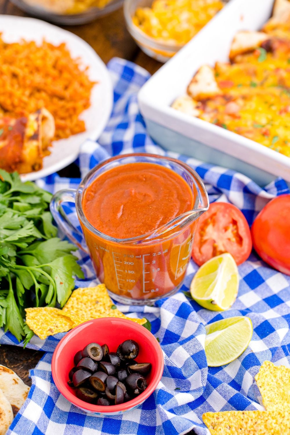 Homemade Enchilada Sauce in container sitting on table with enchiladas in pan to the side of container 