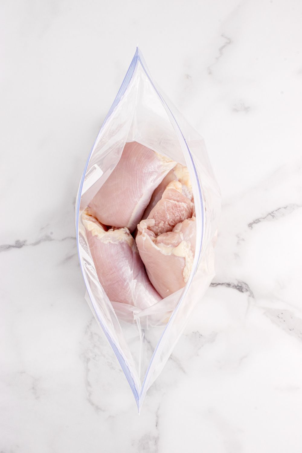 overhead look of raw chicken in a ziplock bag