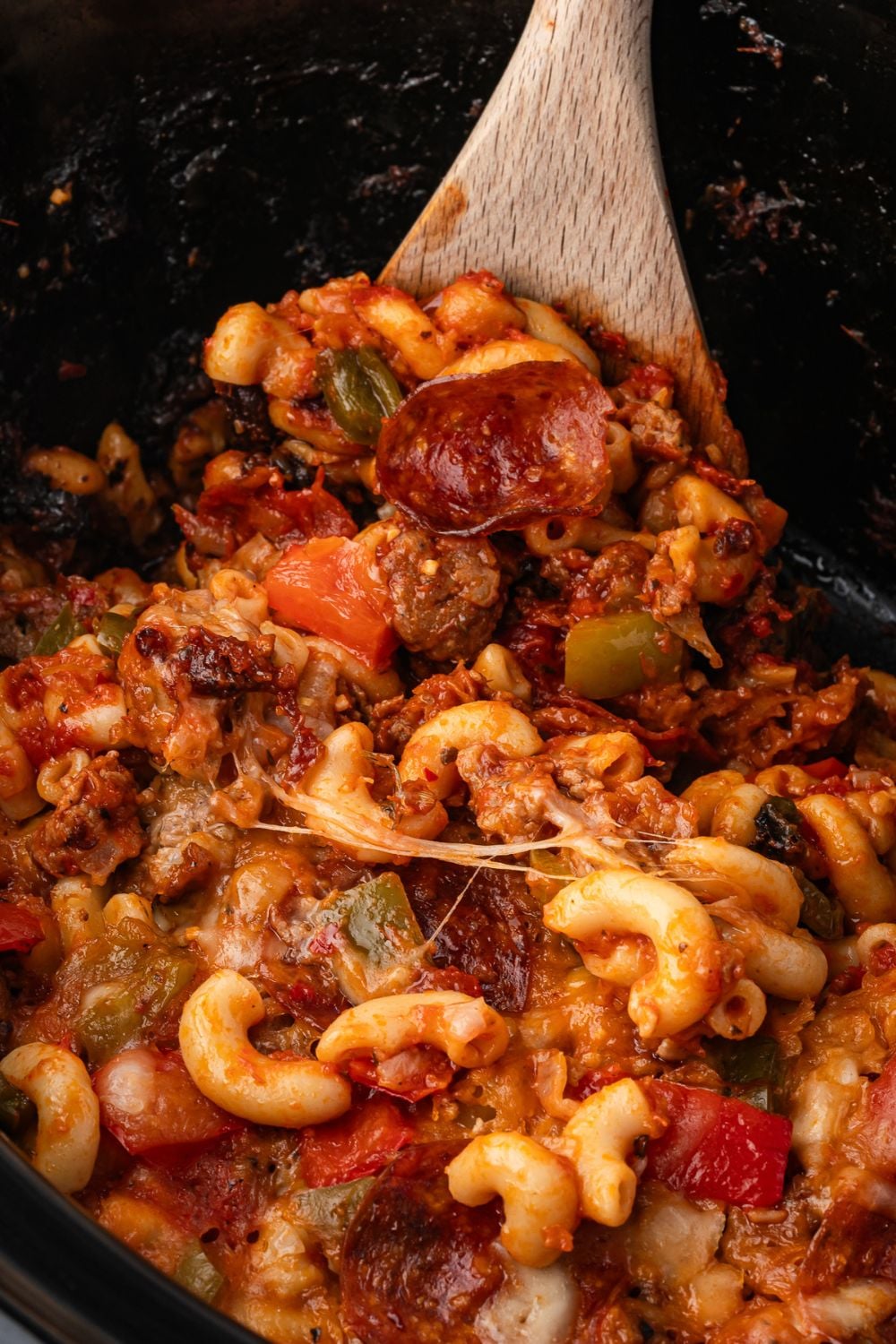 Slow Cooker Pizza Casserole with a spoon being scooped out of crock pot