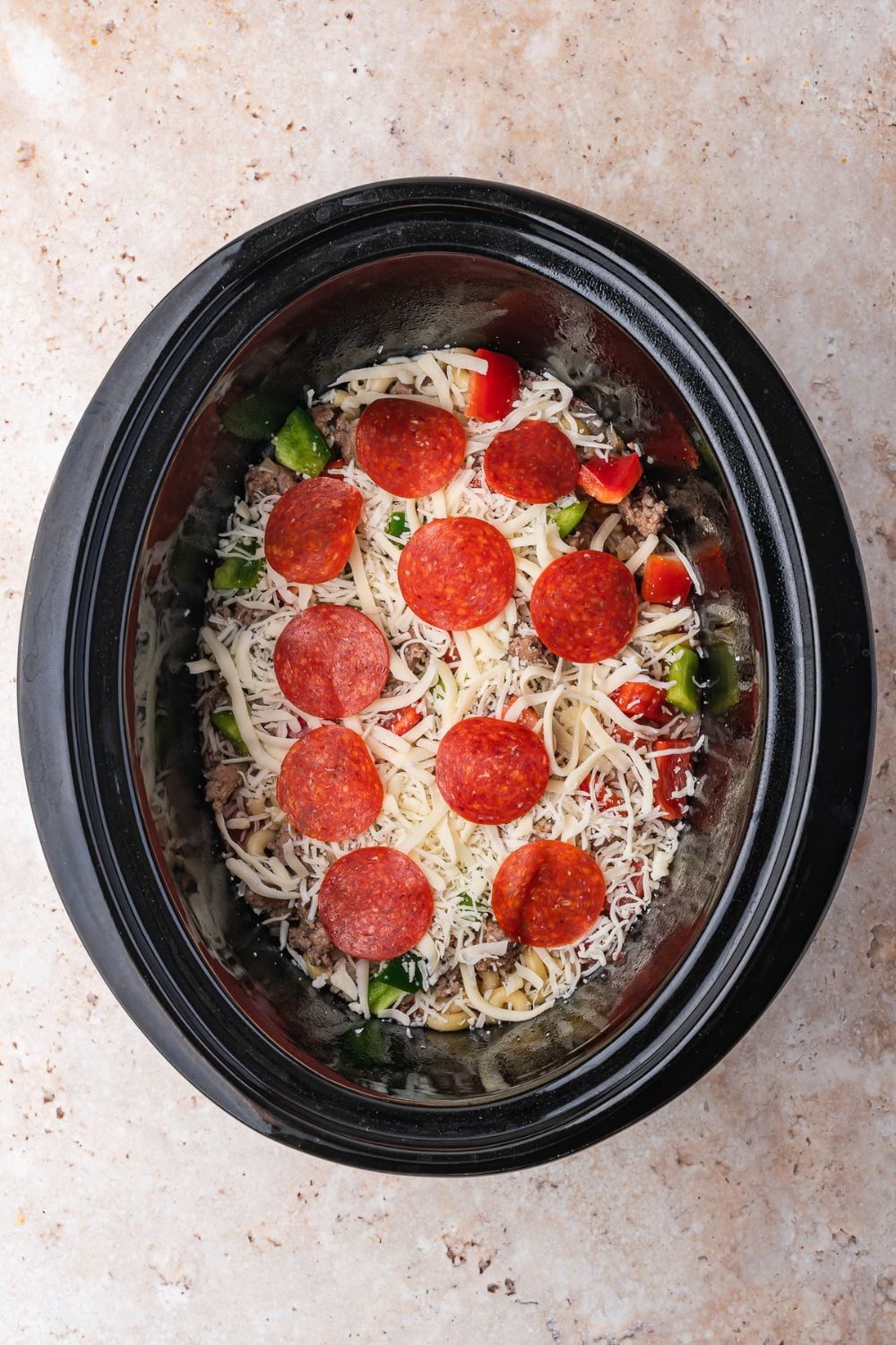 overhead of assembling Slow Cooker Pizza Casserole on table