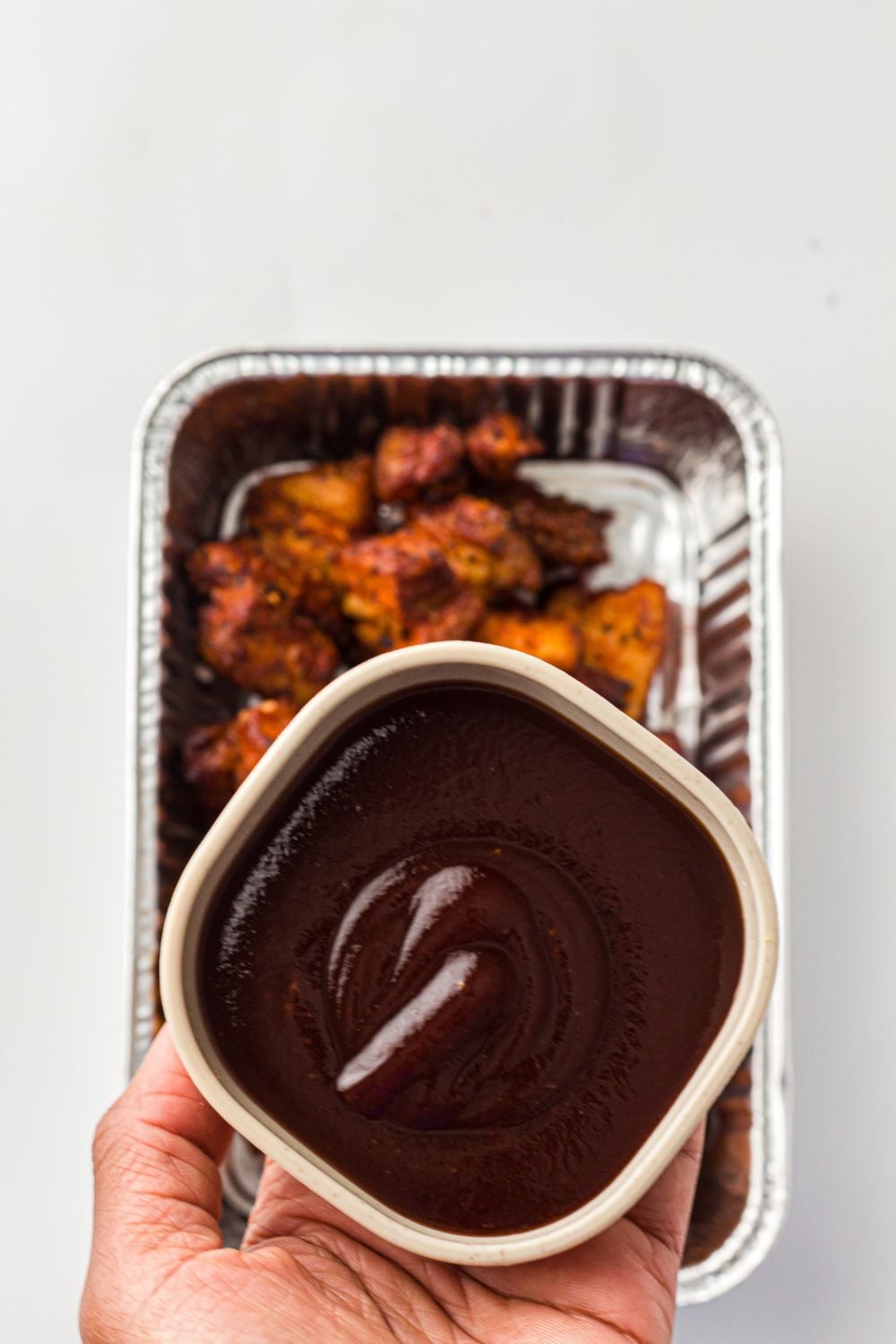 bbq sauce in a bowl placed over a pan of pork belly