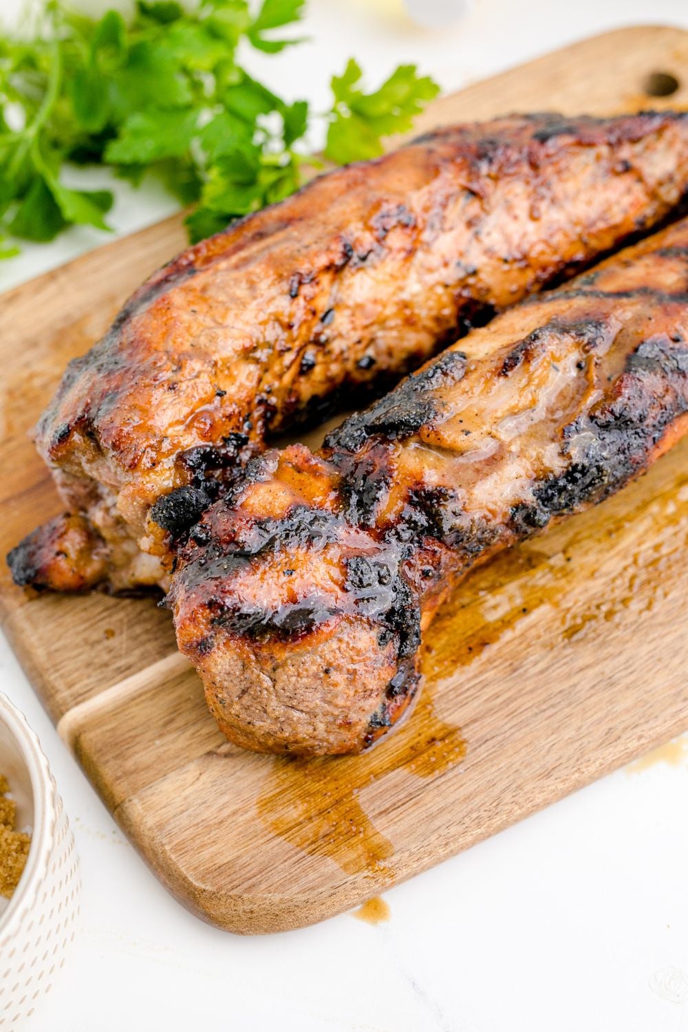 Grilled Pork Tenderloin that is cooked sitting on a wooden cutting board 