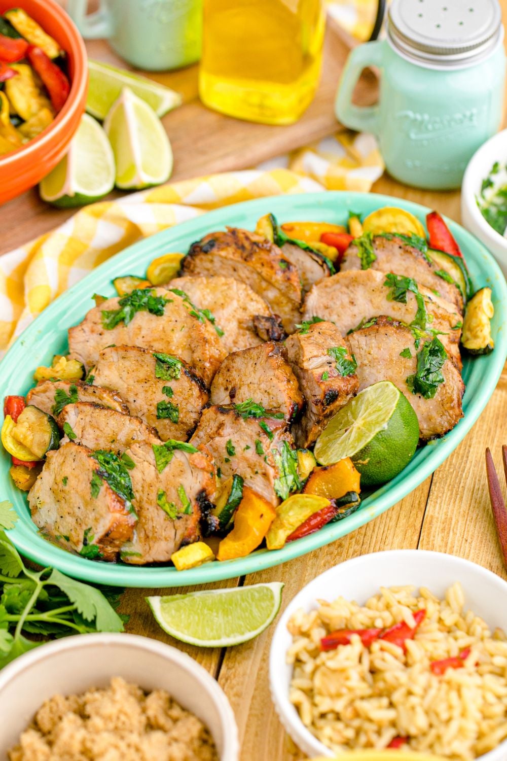 Grilled Pork Tenderloin in a serving tray with rice and other ingredients around it on the table