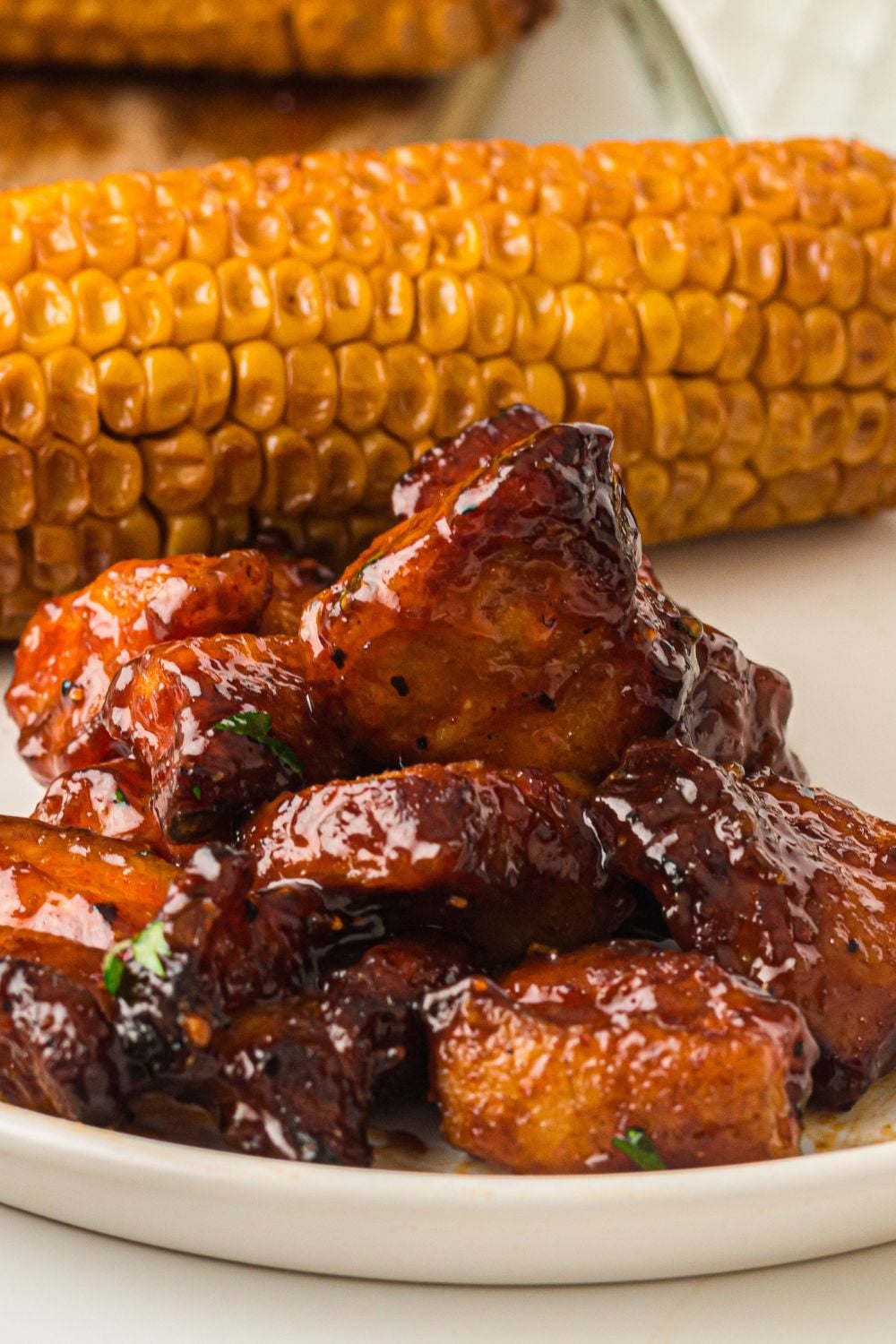 Smoked Pork Belly Burnt Ends on plate with corn on cob as well