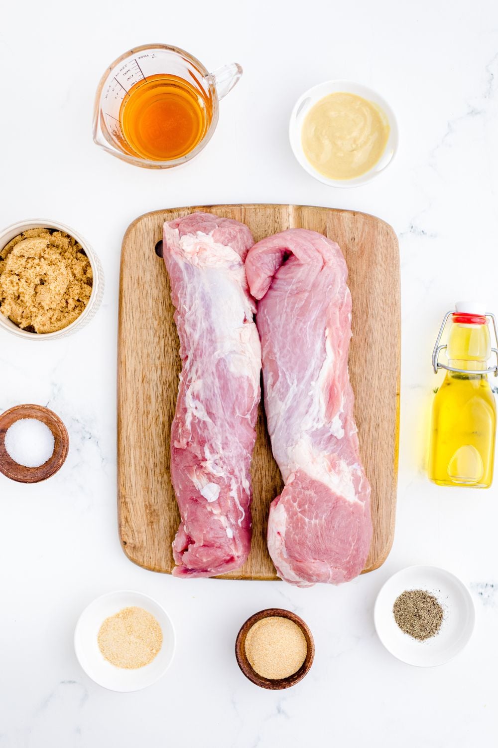 ingredients for grilled pork tenderloin on a cutting board and bowls of ingredients around the cutting board