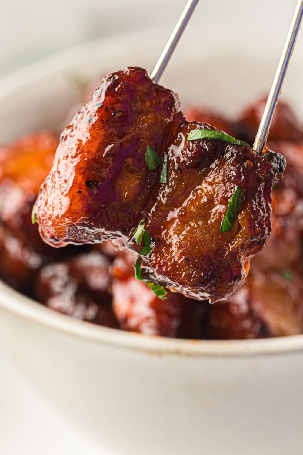 Smoked Pork Belly Burnt Ends in a bowl with metal skewers poked in a few of them